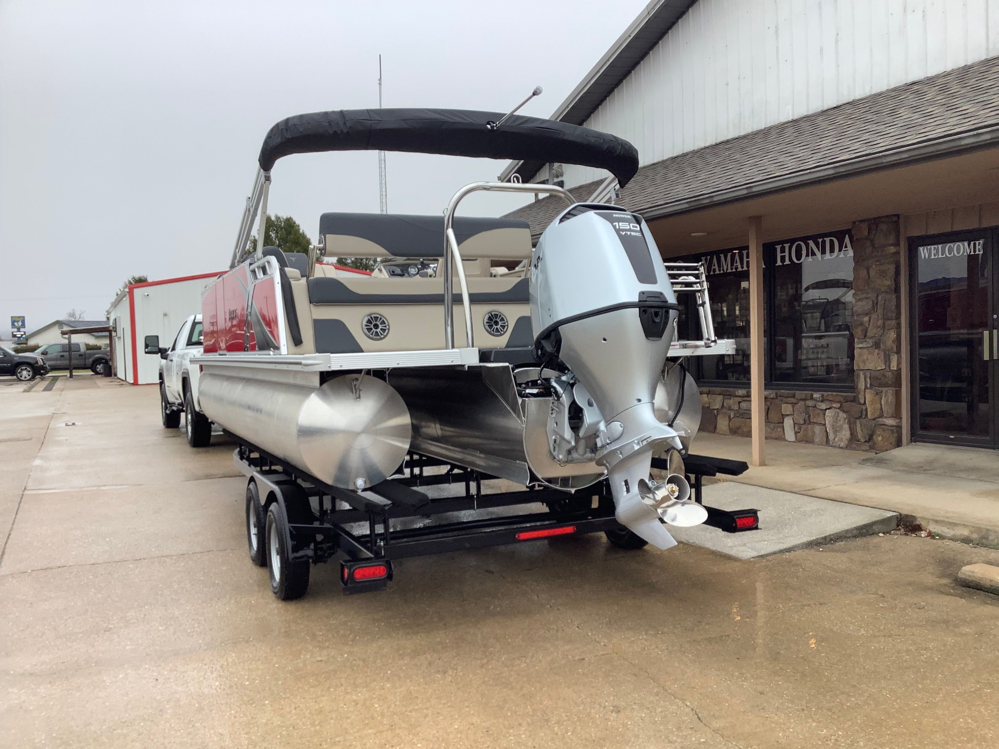 2026 Tahoe 2185 LTZ pontoon boat on trailer outside store.
