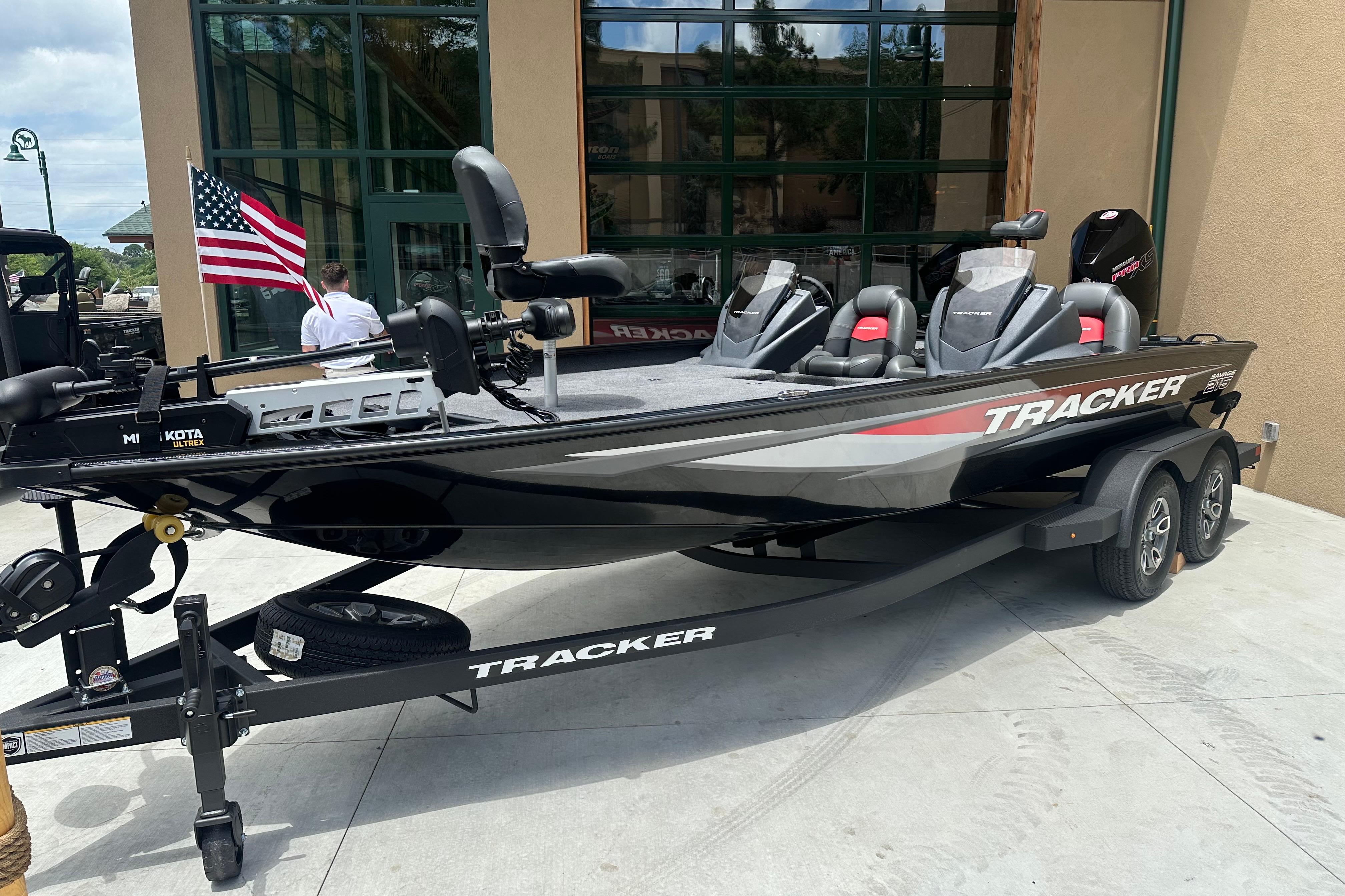 2025 Tracker Savage 215 boat on trailer, displayed outdoors with American flag.