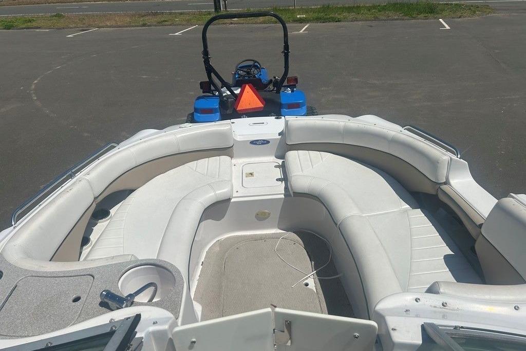 2006 Four Winns 244 Funship boat with spacious seating, parked on pavement.