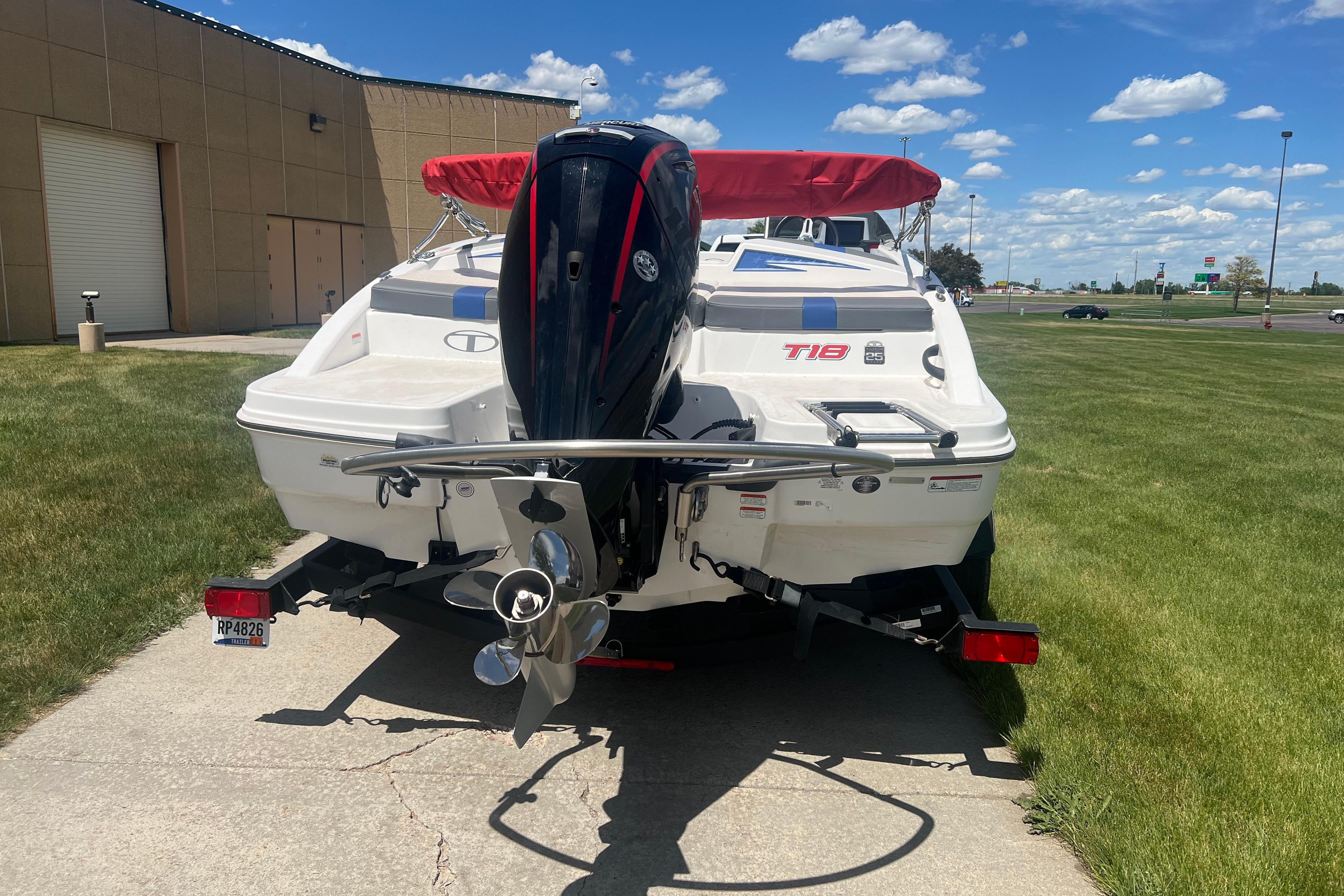 2023 Tahoe T18 boat with outboard motor on trailer, parked on grass.