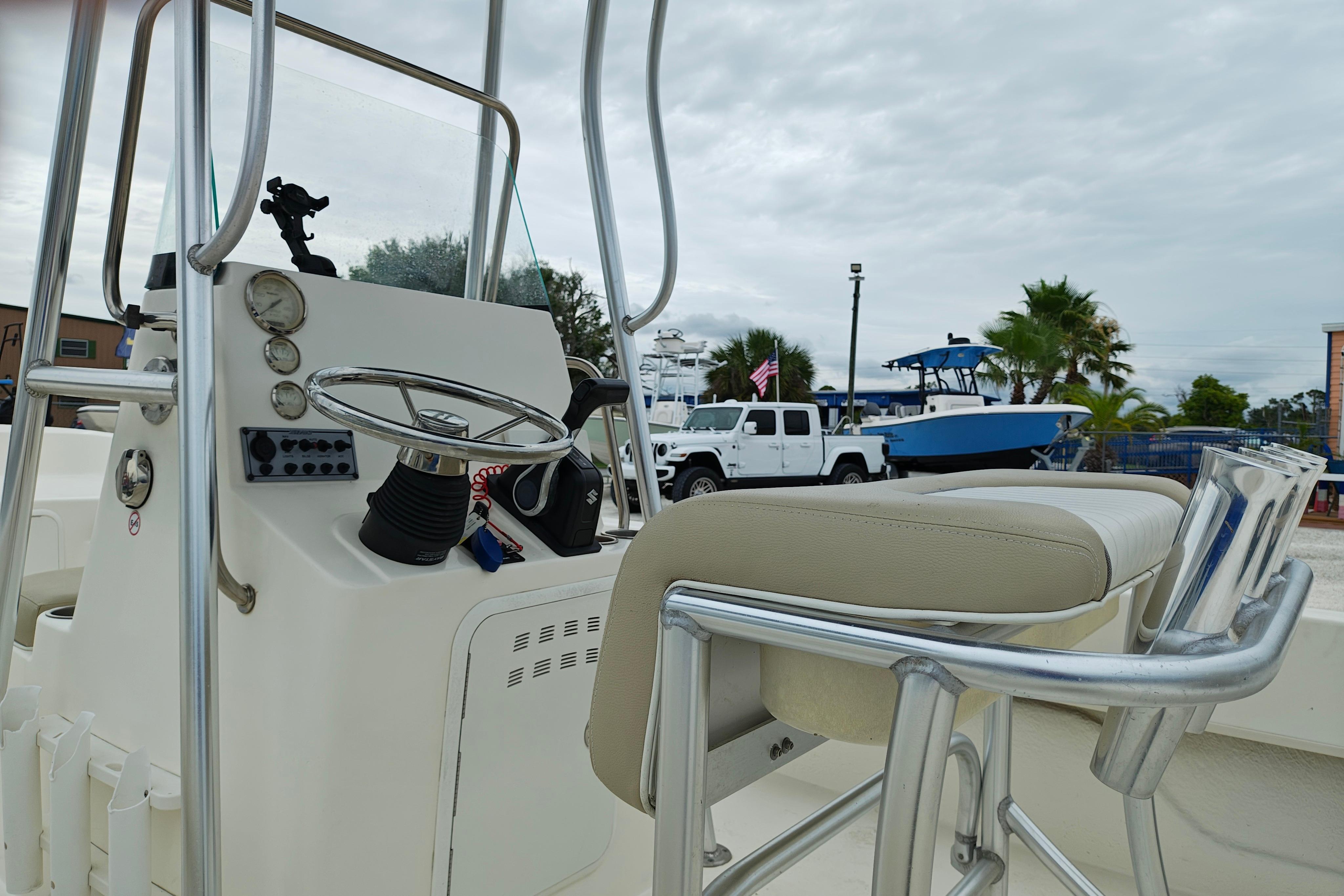 2018 Sundance B20CCR boat interior with steering wheel and seating, parked near vehicles and palm trees.