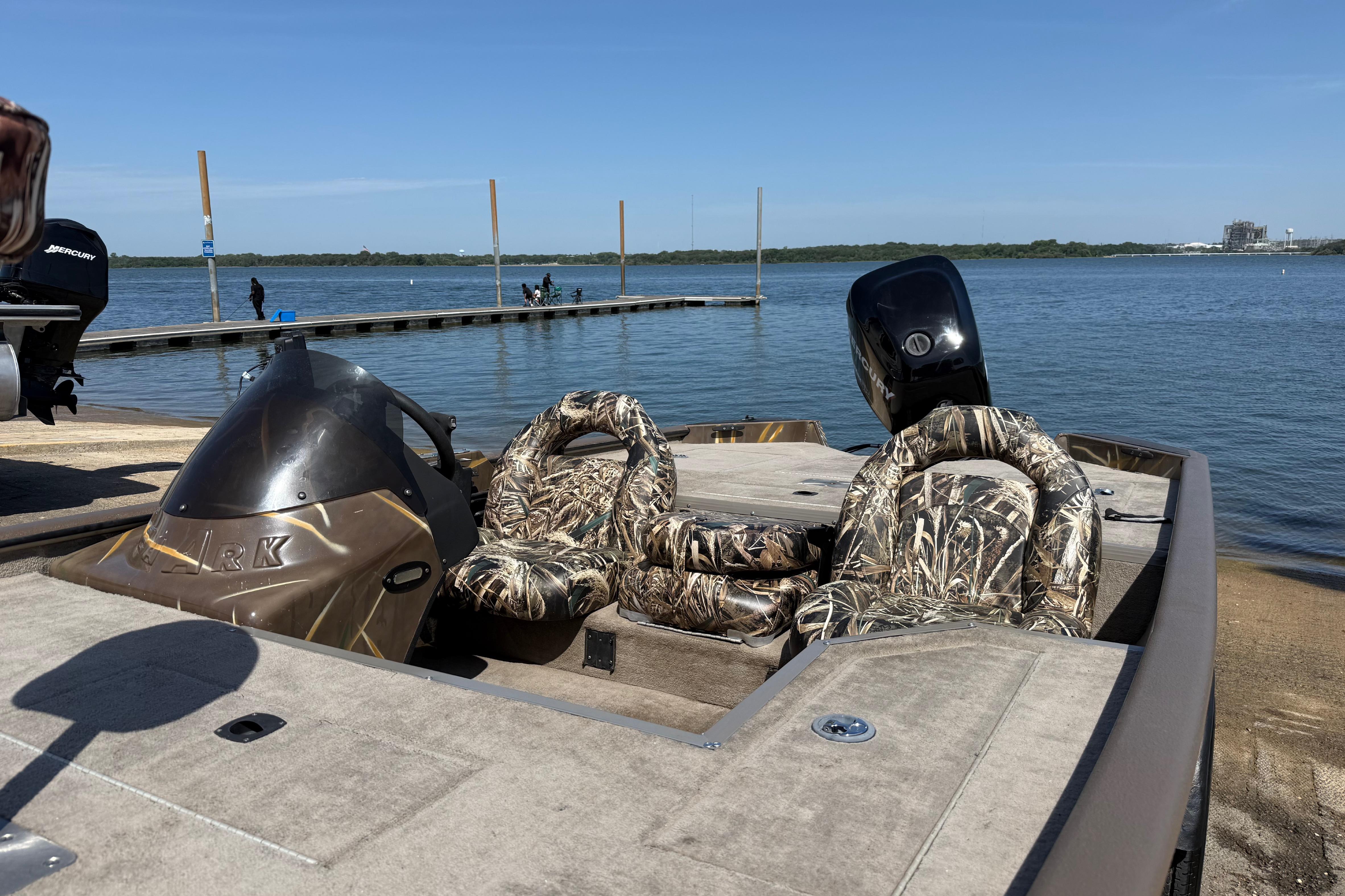 2010 SeaArk Stealth 190 boat with camouflage seats docked by a serene lake.
