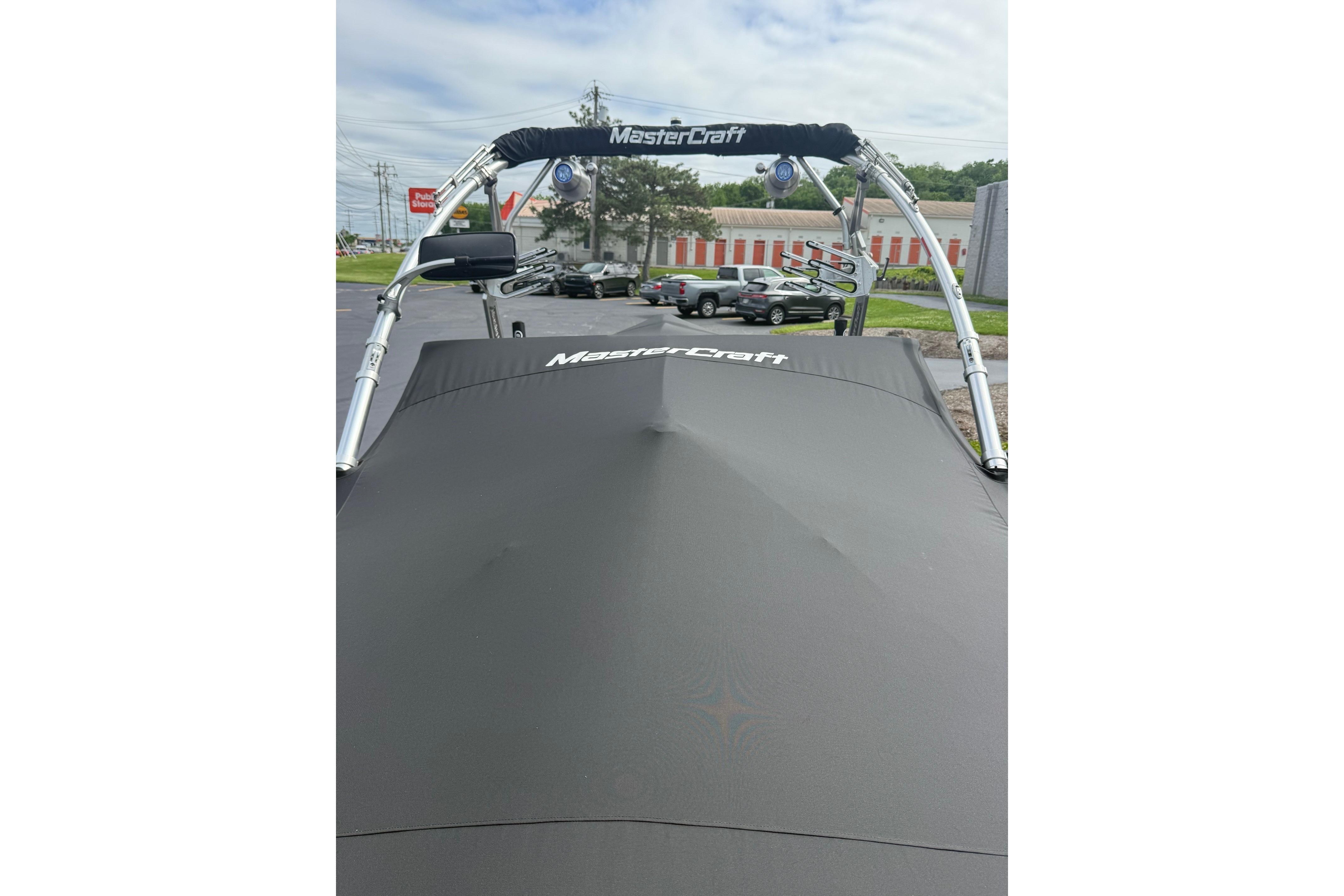 2008 MasterCraft X-15 boat with cover, parked outdoors, showcasing sleek design and branding.