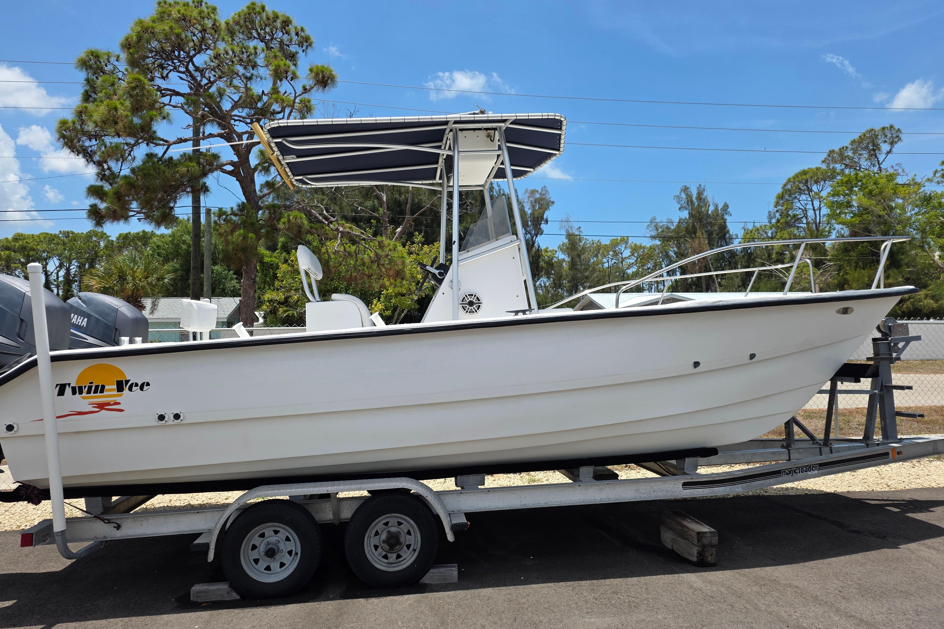 1999 Twin Vee Awesome 22 boat on trailer, featuring a sleek white design and canopy.