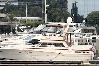 1980 Viking 43 Convertible yacht docked at a marina with modern buildings in the background.