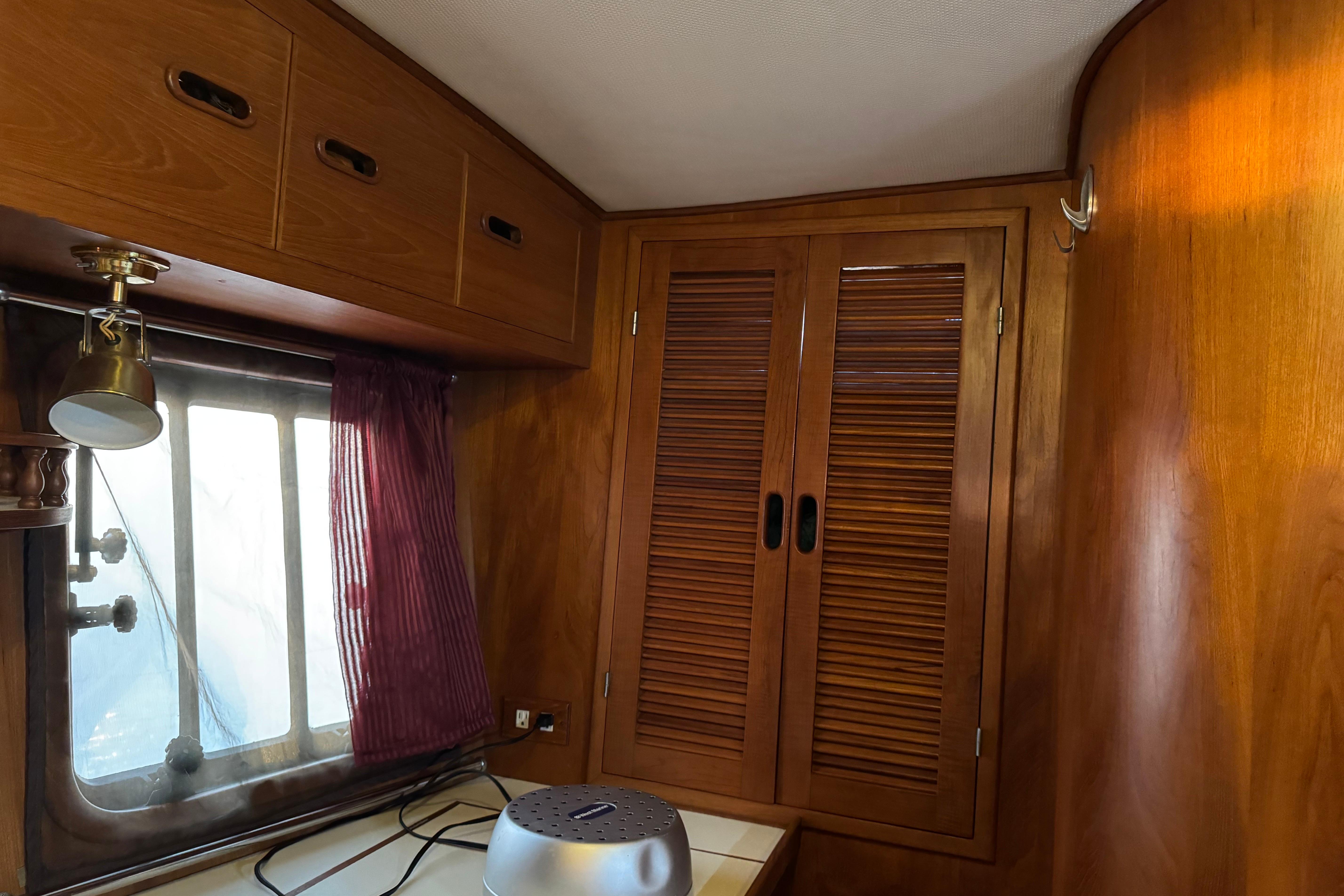 Wood-paneled interior of a 1987 President 37 boat with window and storage cabinets.