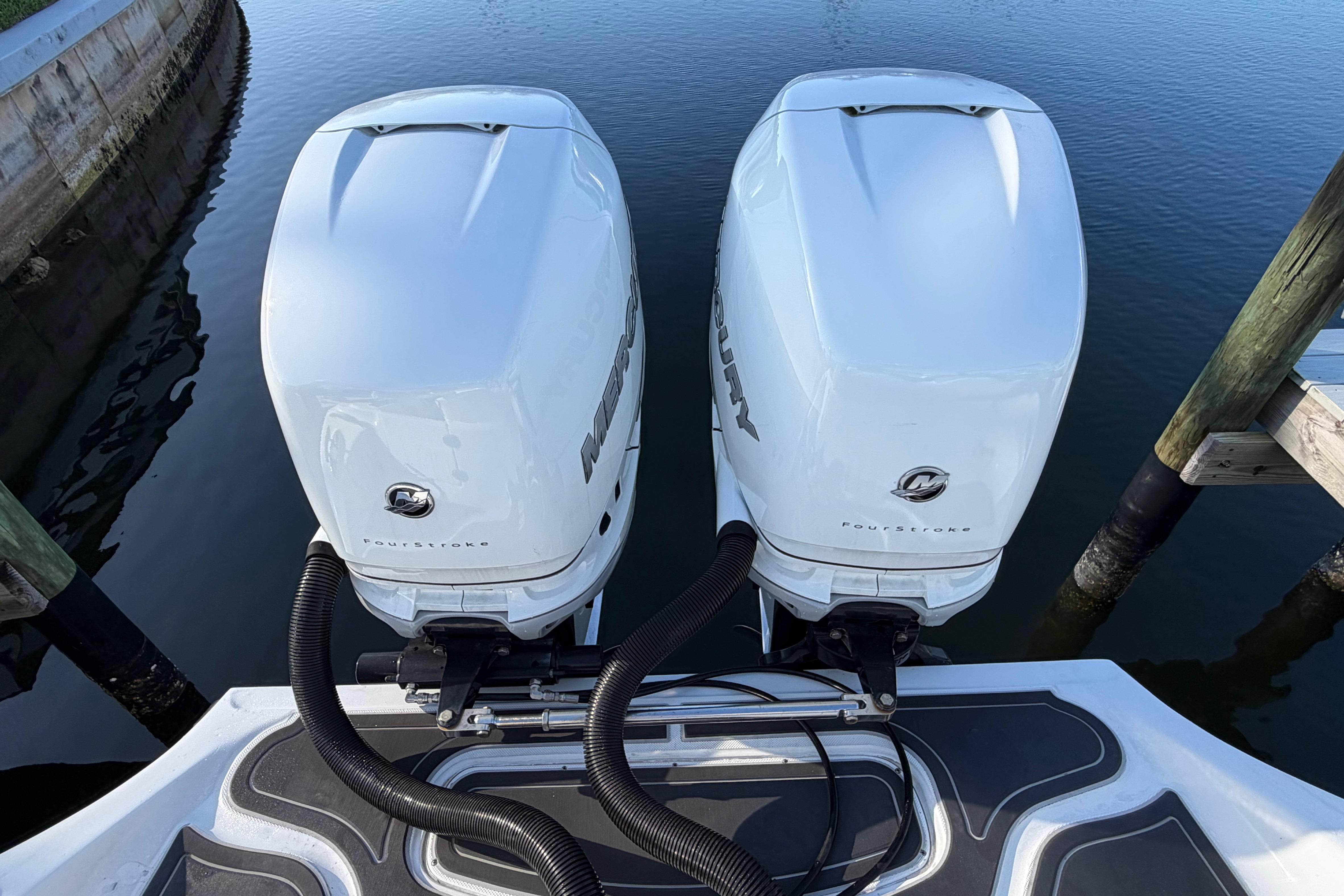 Twin Mercury outboard engines on a 2022 Glasstream 328 Pro-XS boat, docked by calm water.