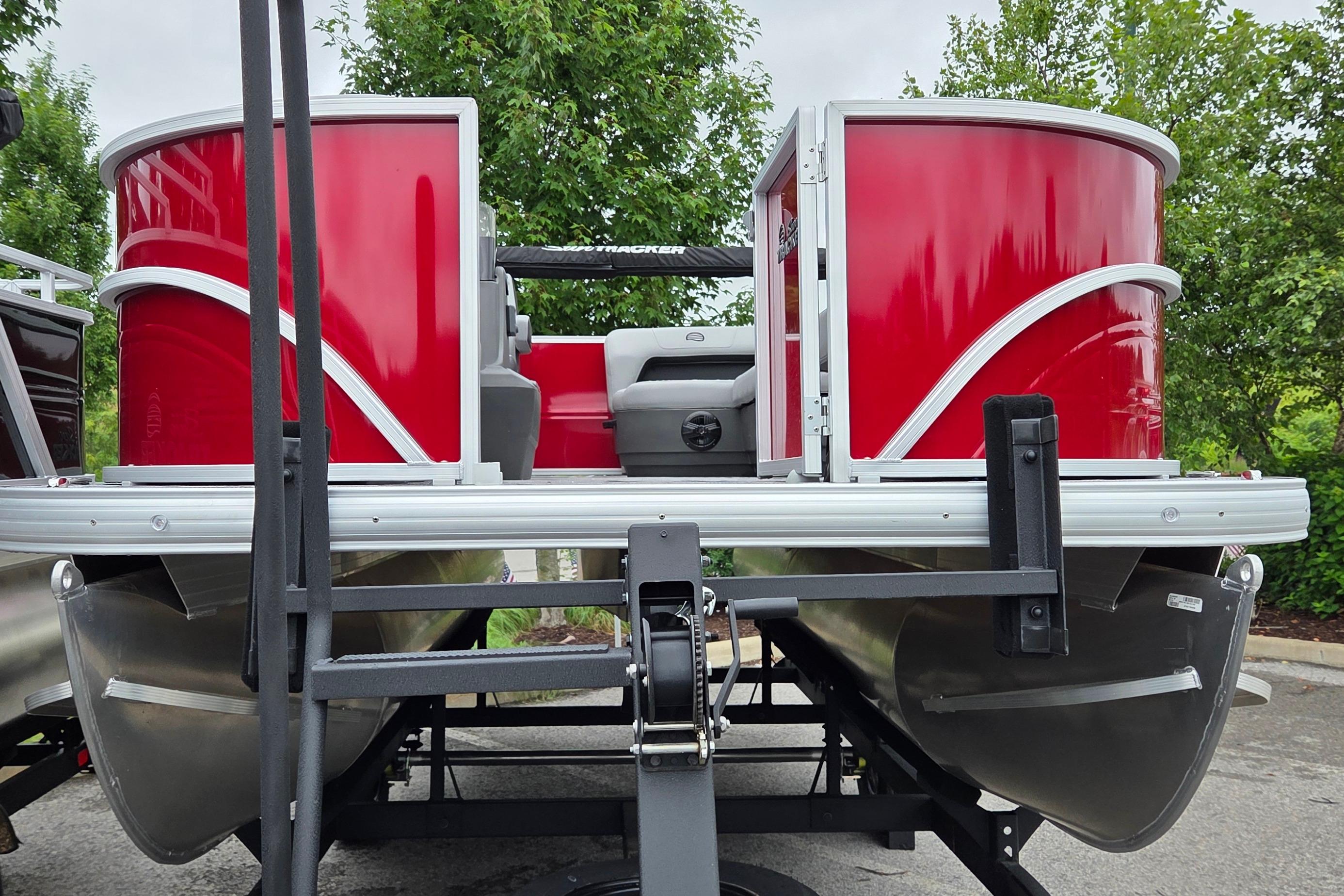 2026 Sun Tracker Party Barge 16 DLX pontoon boat with vibrant red exterior on trailer.