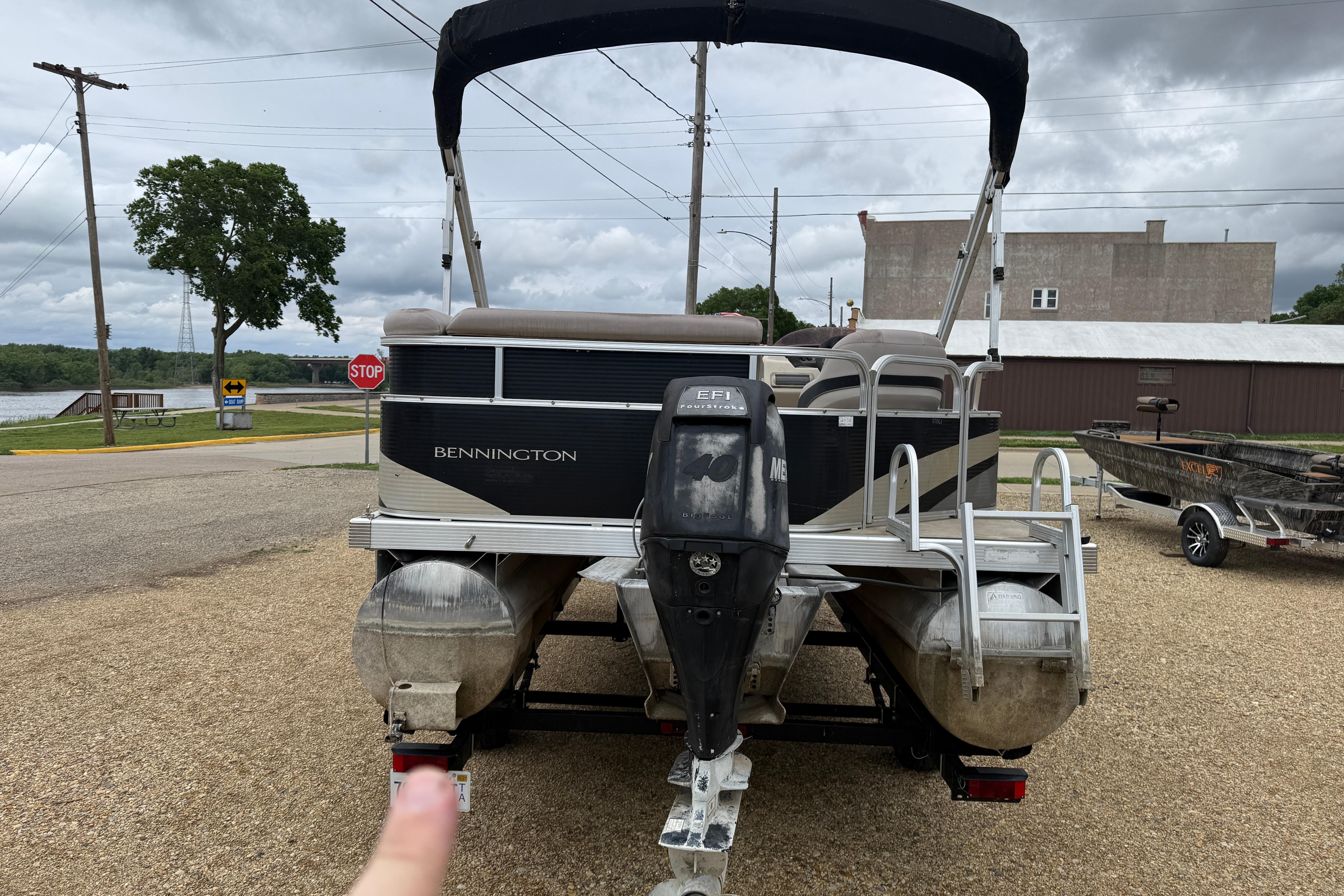 2010 Bennington 20SLi pontoon boat with canopy, parked on gravel near a lake.
