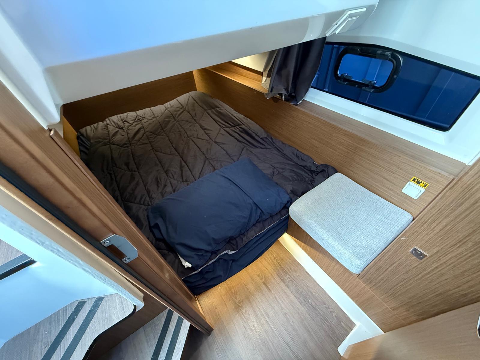 2021 Jeanneau NC Weekender 1095 cabin interior with cozy bed and wooden finish.