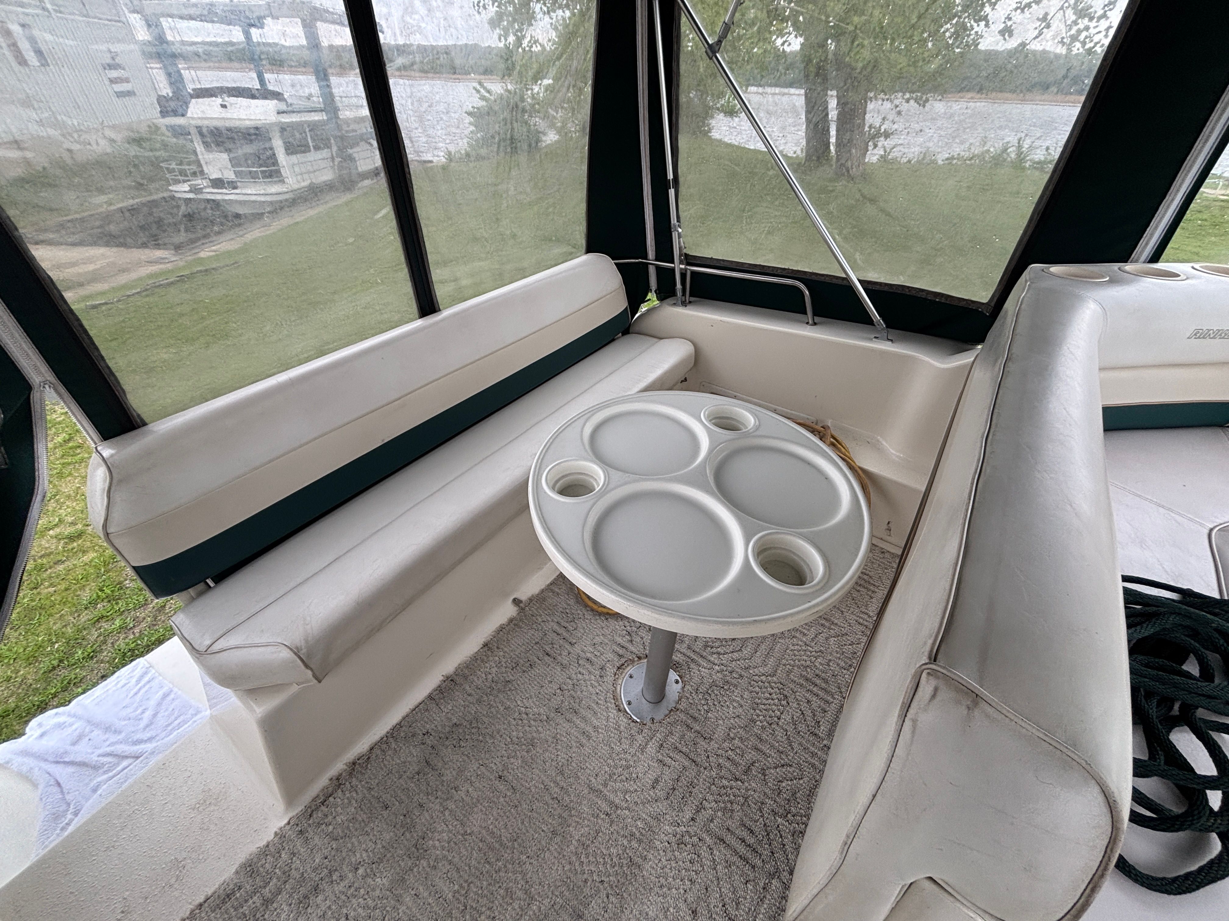 Interior view of a boat with white seating and a round table.