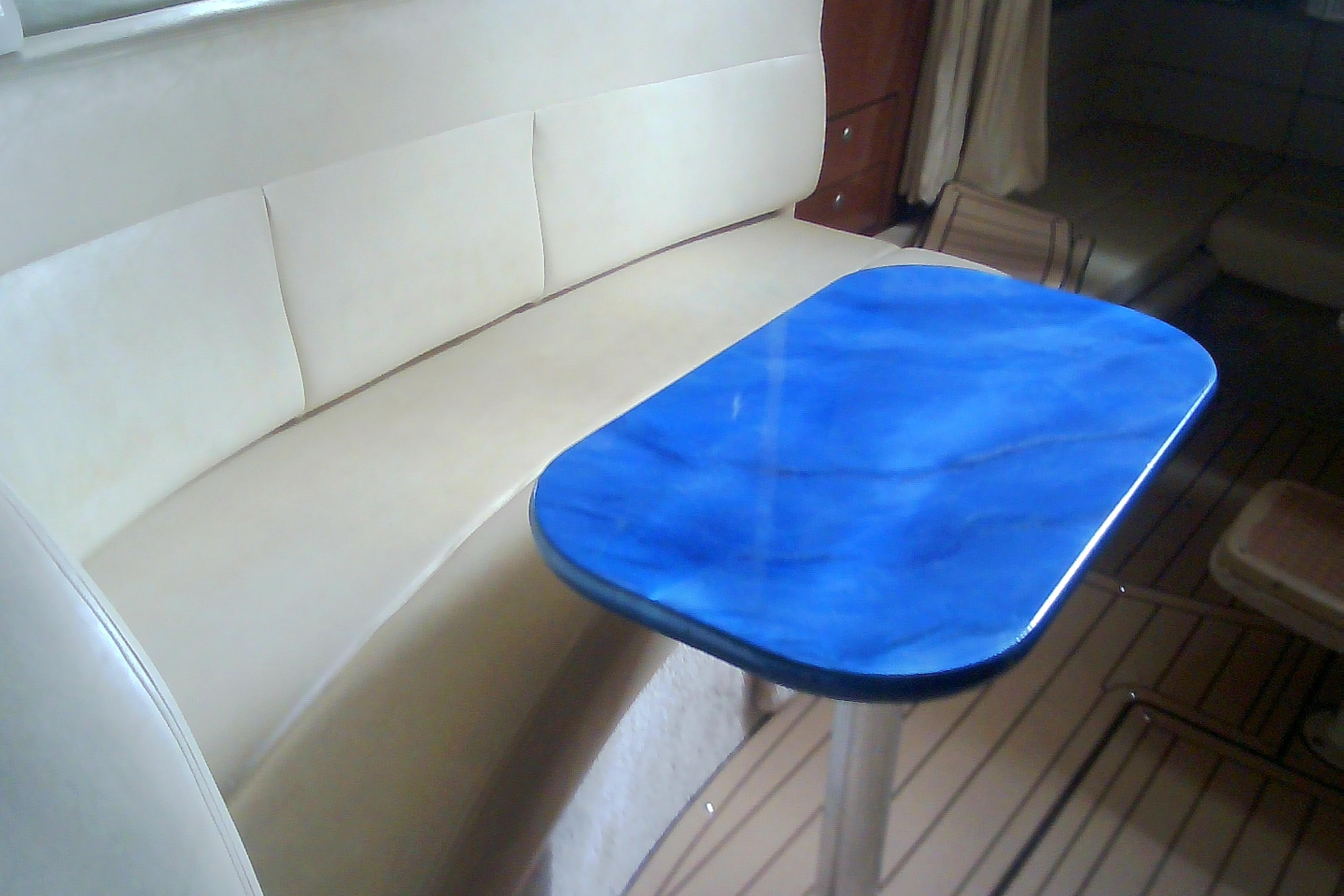 Interior of 2005 Sea Ray 300 Sundancer with blue table and beige seating.