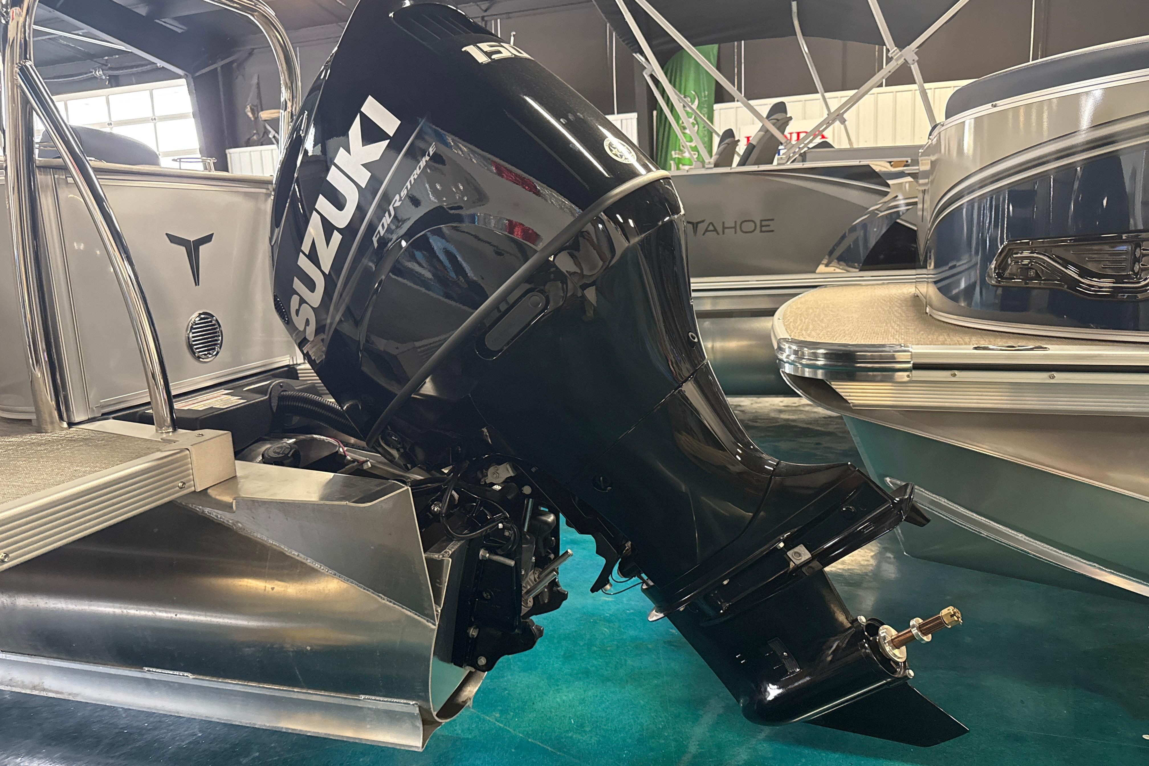 2026 Tahoe Pontoon LTZ Quad Lounger with Suzuki outboard motor in showroom.