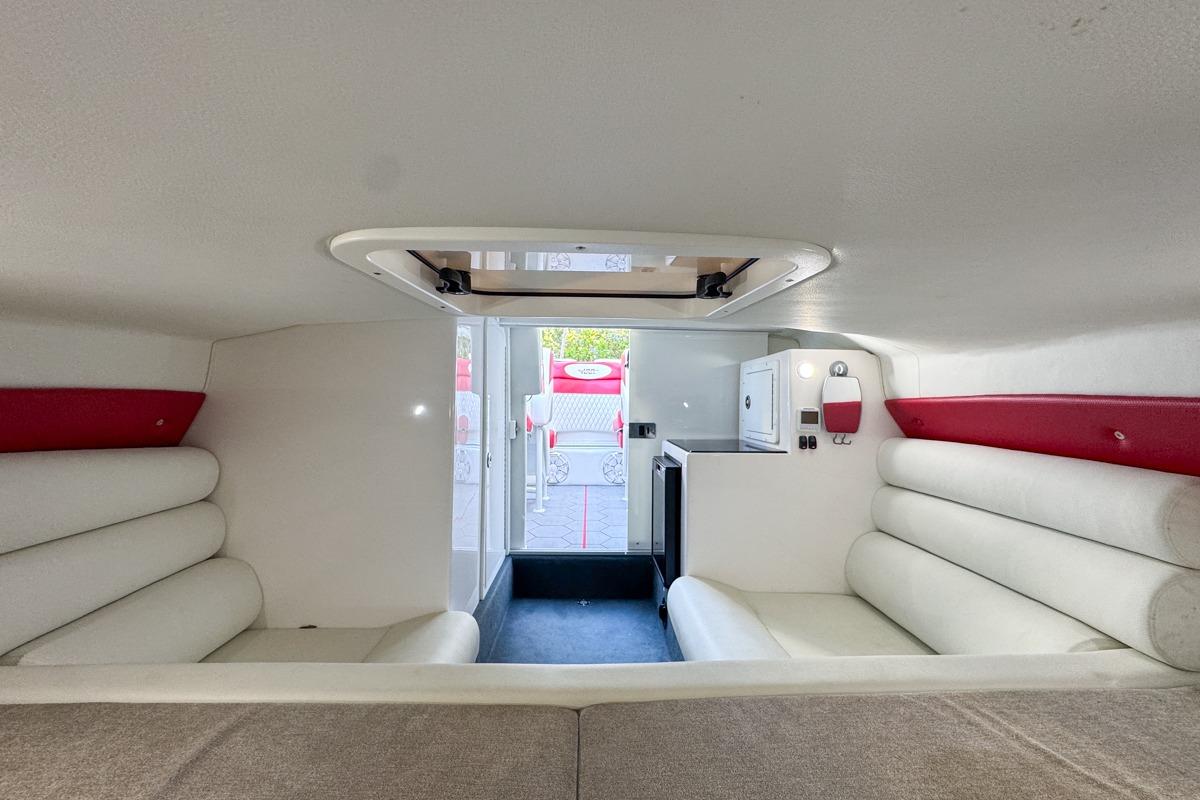 2022 Velocity 290sc boat interior with white and red seating, compact kitchenette.