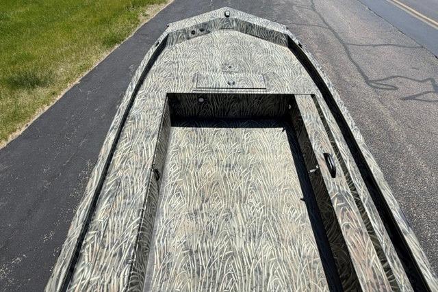 2026 Tracker Grizzly 1654 T Sportsman boat with camouflage interior design on a road.