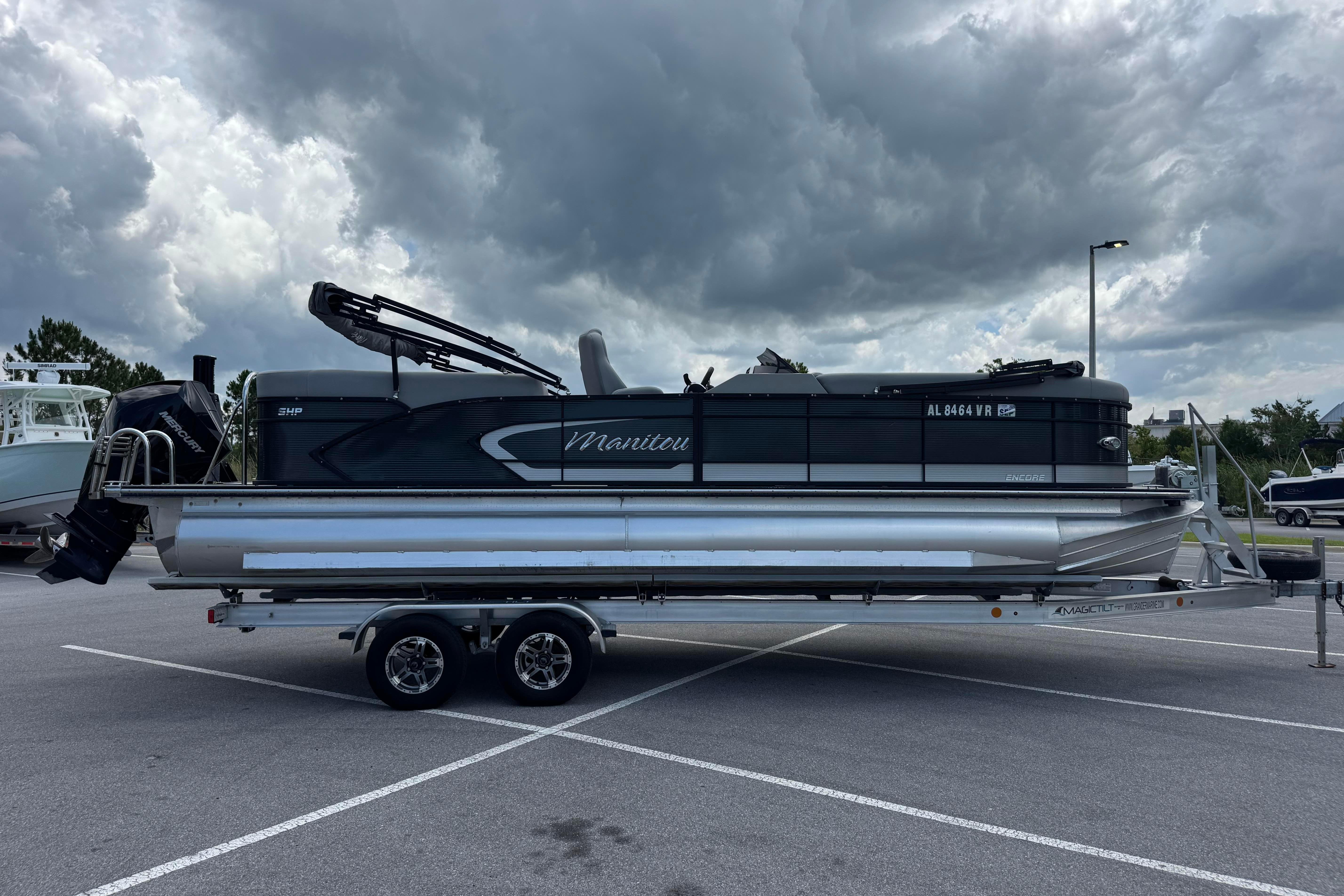 2022 Manitou 25 Encore pontoon boat on trailer under cloudy sky.
