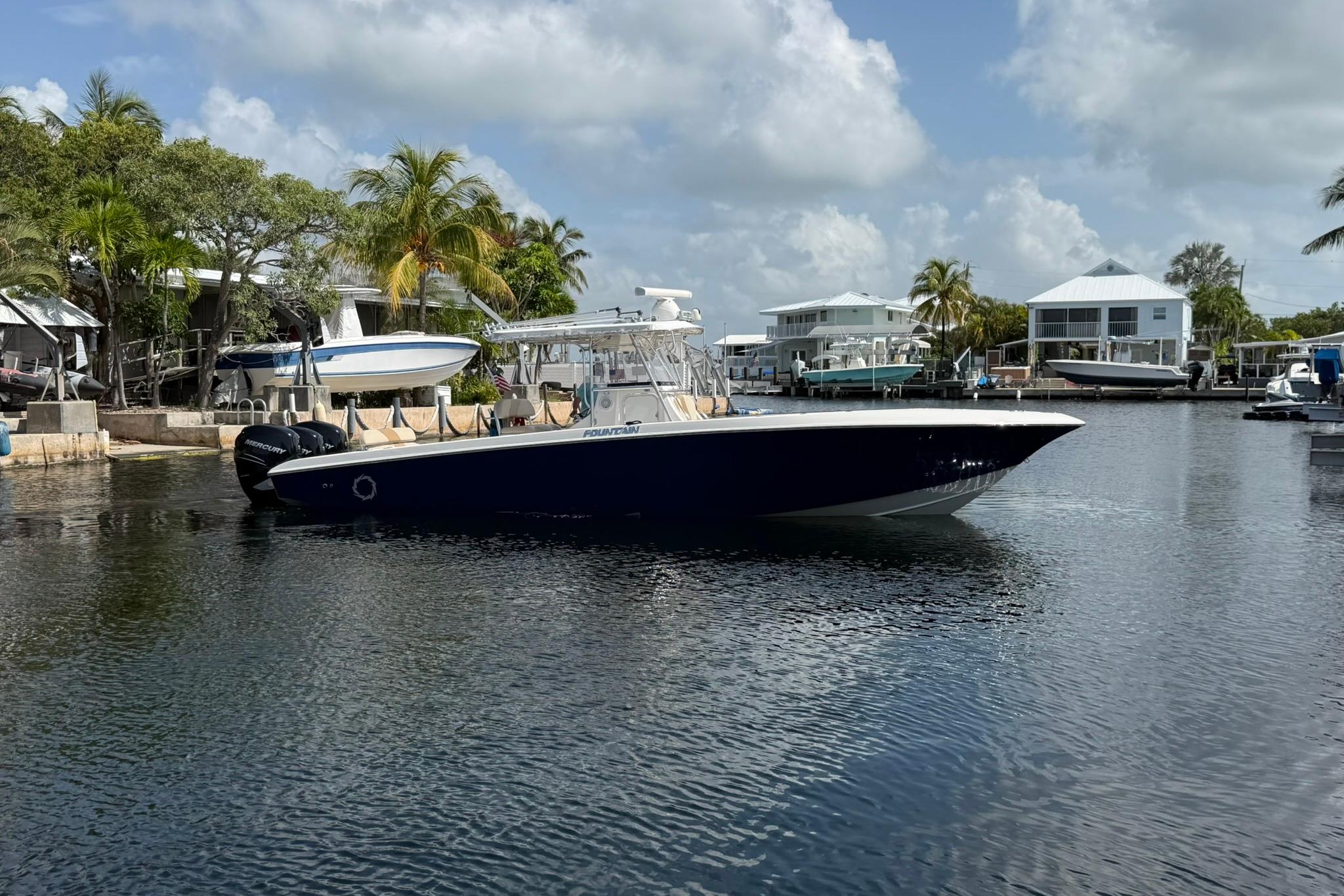 2007 Fountain 34 Center Console boat docked in a scenic marina with palm trees.
