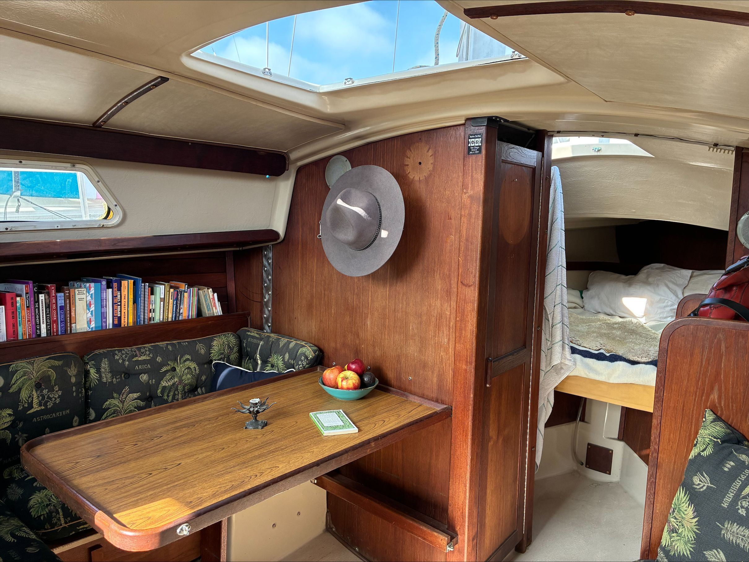 Interior of a 1980 Newport 30 with a cozy seating area and bookshelf.