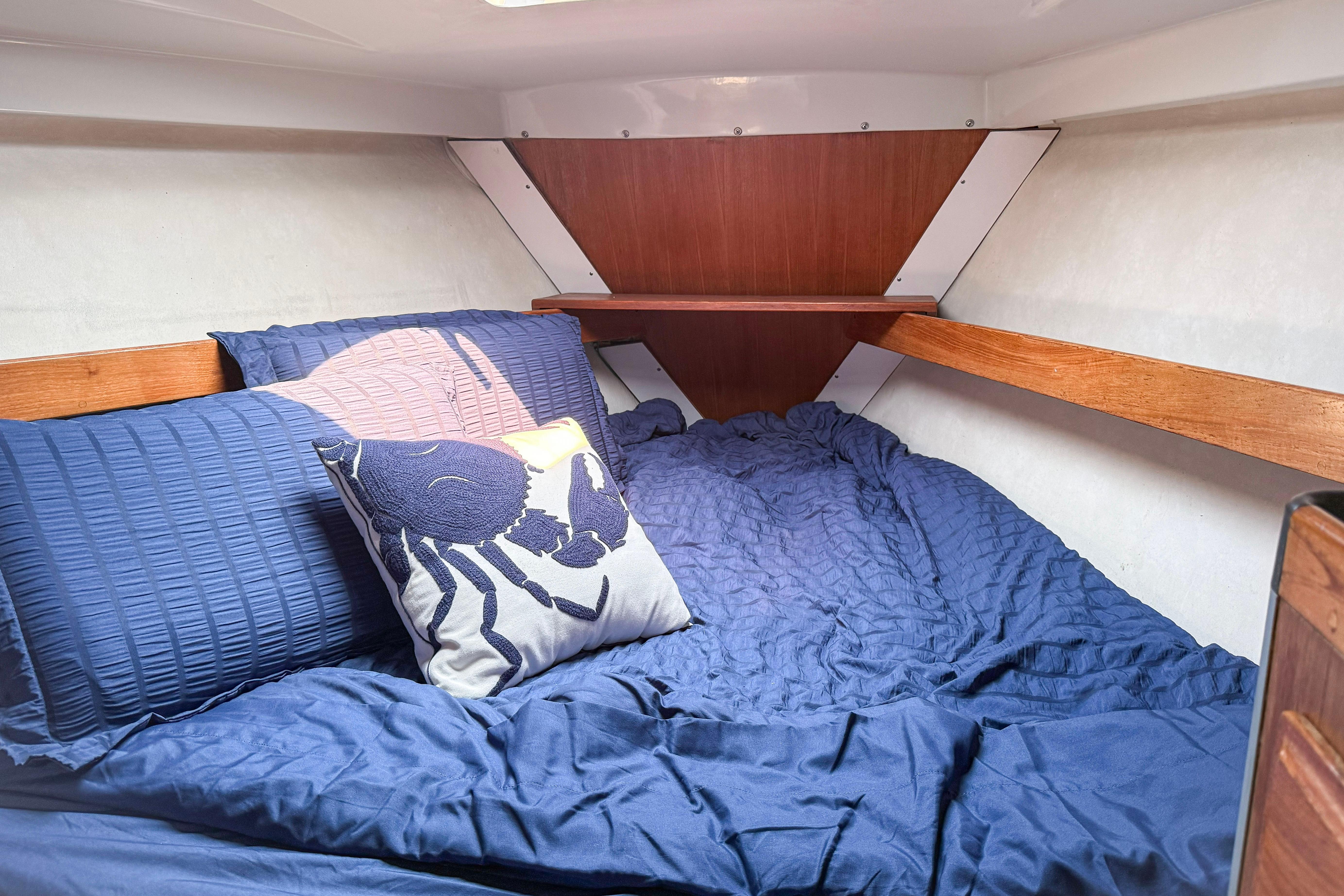 Cozy cabin interior of 1988 Oday 40 sailboat with blue bedding and decorative pillow.
