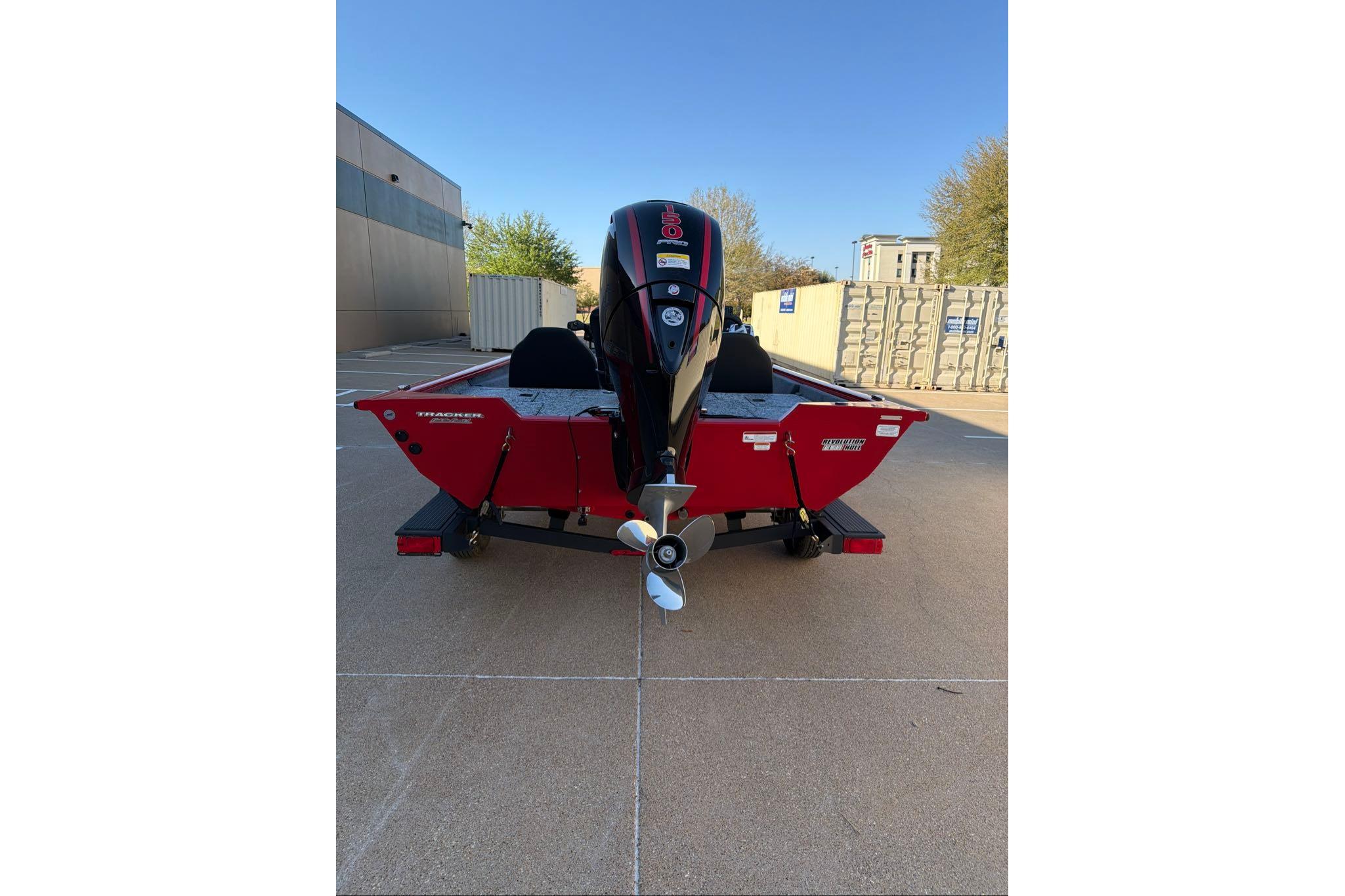 2026 Tracker Pro Team 195 boat, red exterior, parked outdoors with visible outboard motor.