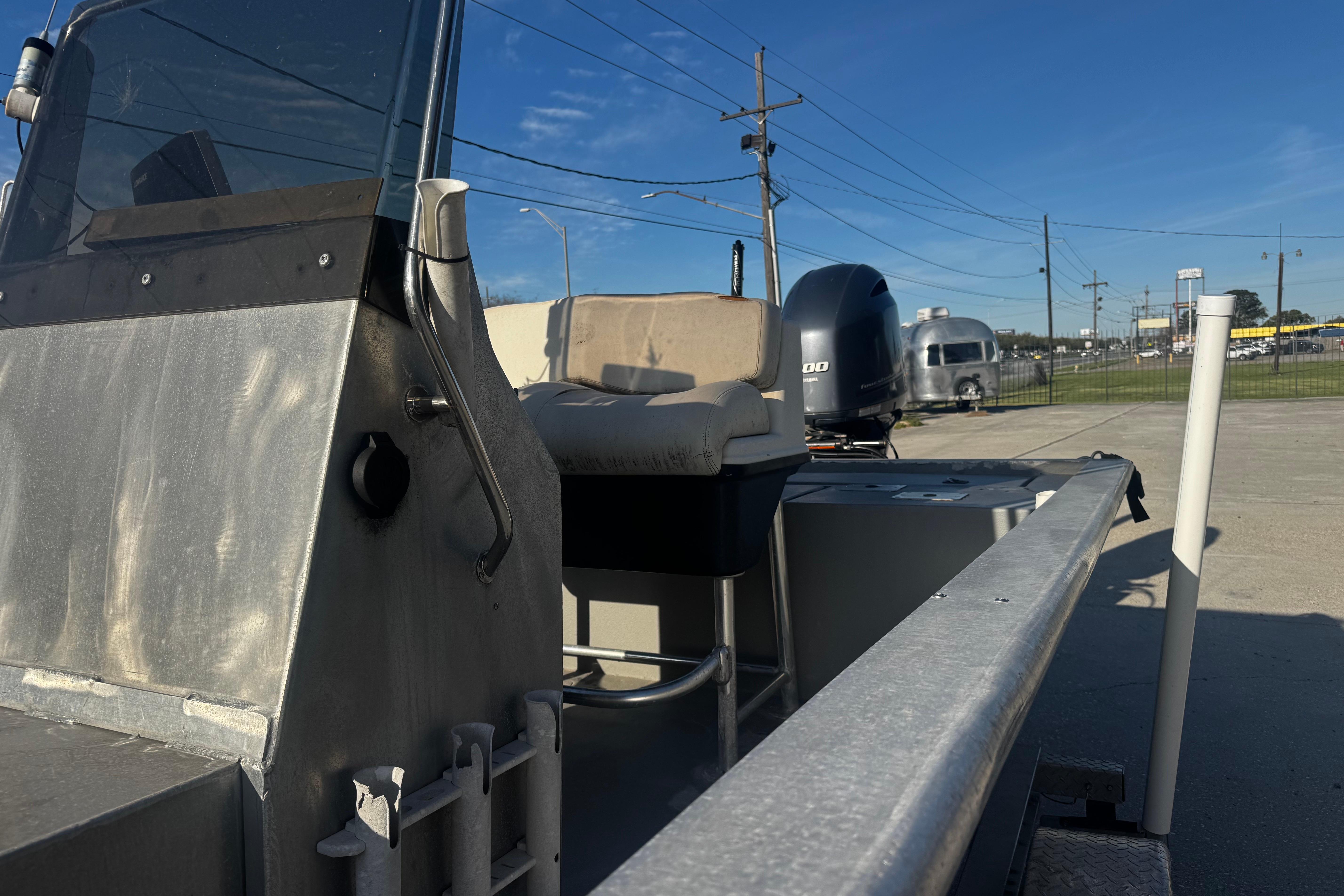 Aluminum boat with console and seat, Custom Charles Leonard 21, 2004 model, parked outdoors.