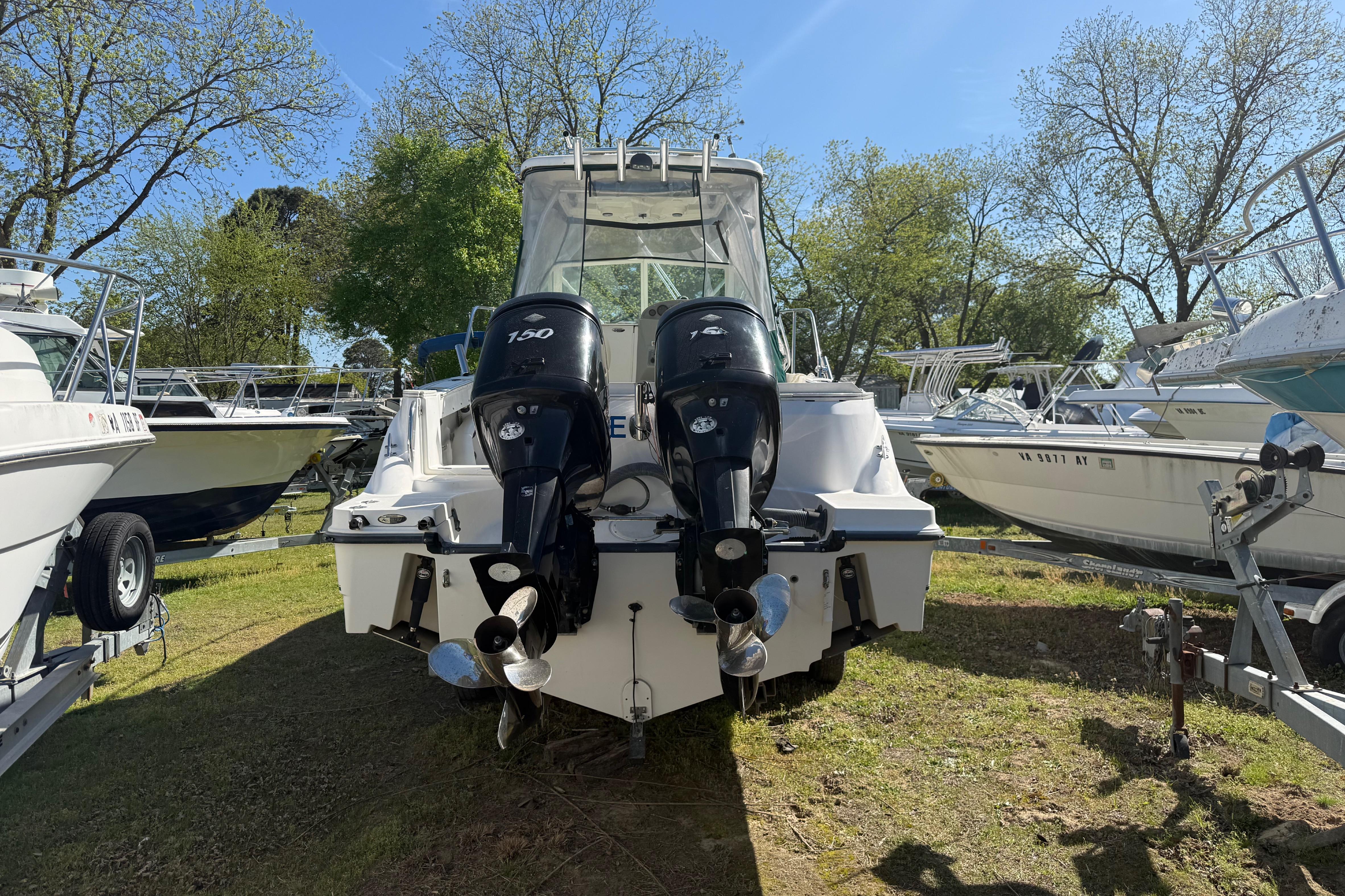 2006 Trophy 2502 Walkaround boat with dual outboard motors, parked on grass.