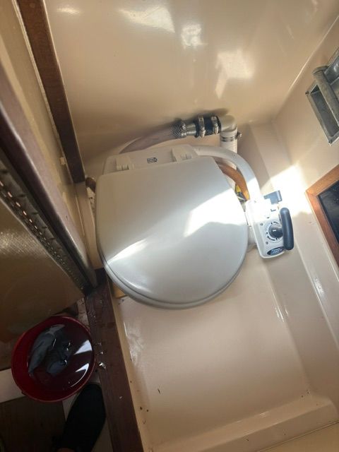 A boat bathroom with a toilet and a bucket.