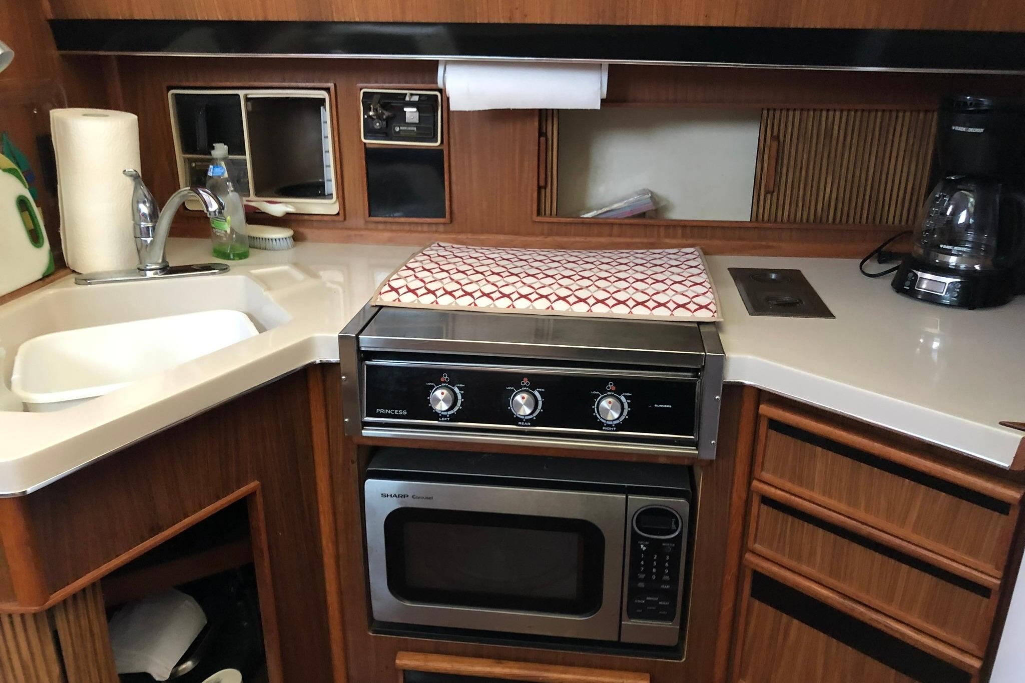 1988 Sea Ray 415 Aft Cabin kitchen with stove, microwave, sink, and coffee maker.