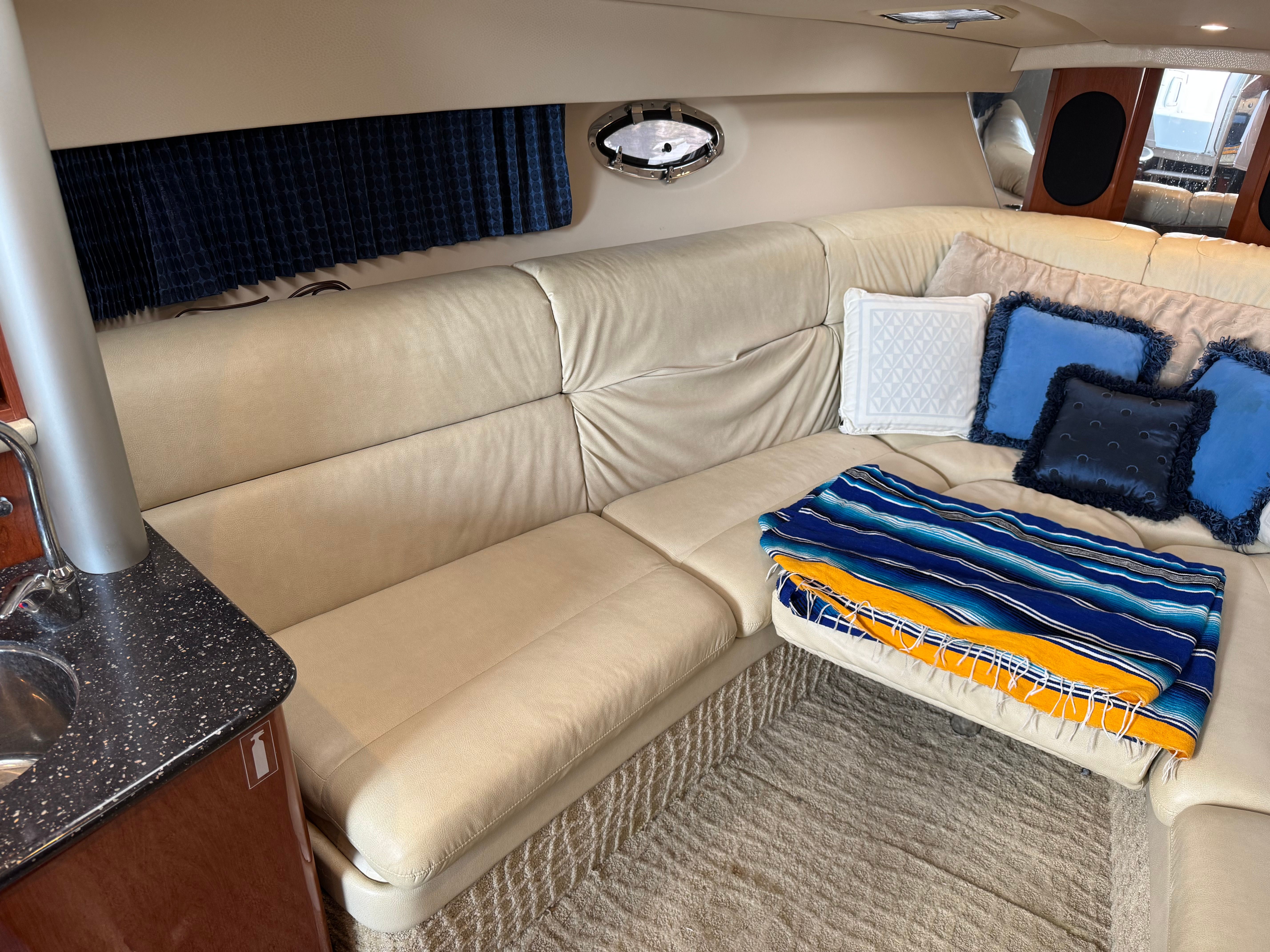 Interior of a yacht with beige sofa and colorful cushions.