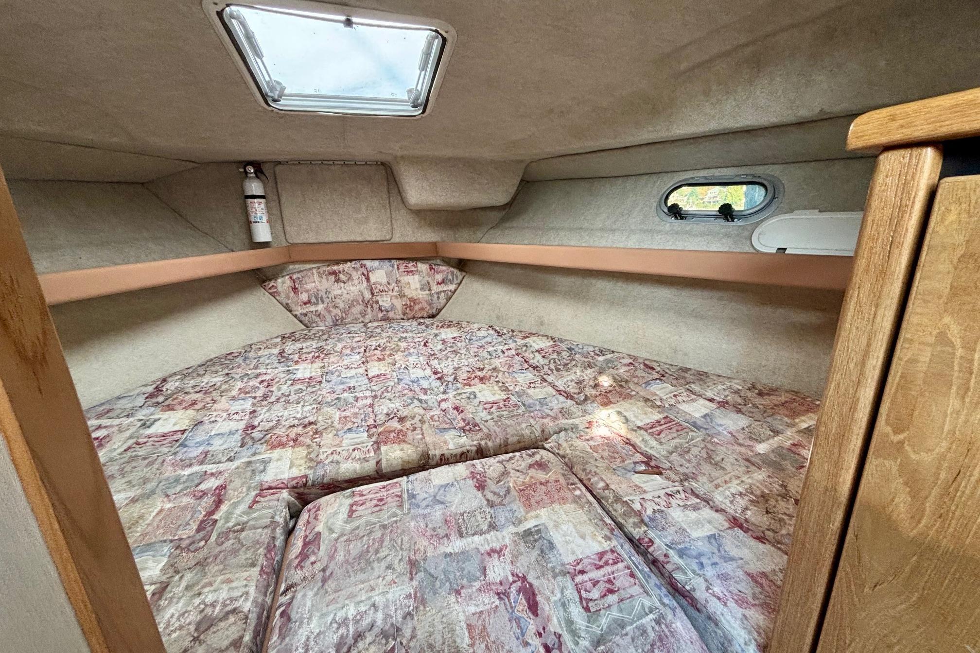 1998 Bayliner 3388 Command Bridge Motoryacht cabin interior with patterned bedding and porthole window.
