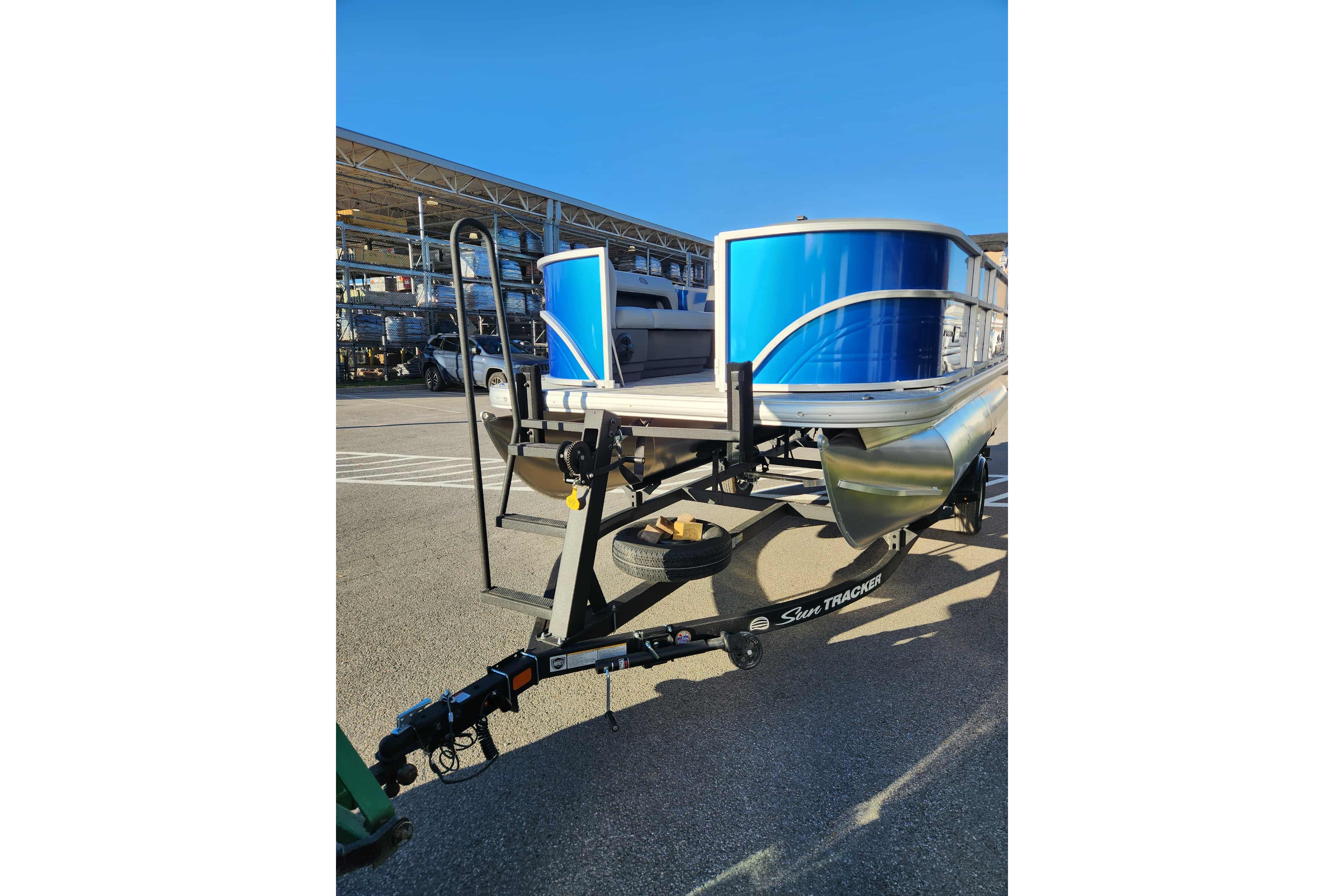 2026 Sun Tracker Party Barge 16 DLX pontoon boat on trailer, parked outdoors.