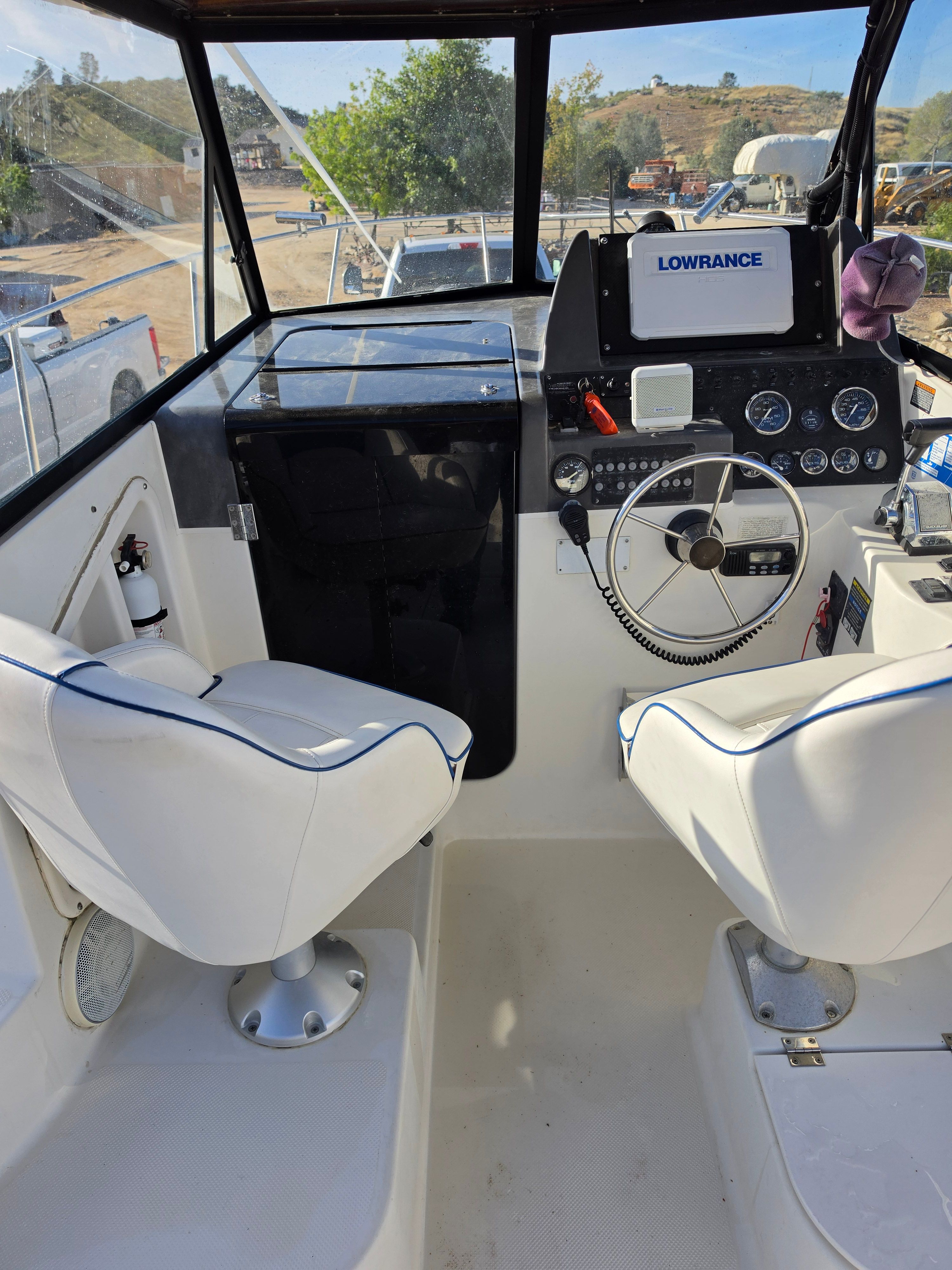 The cockpit of the 2001 Bayliner 2352 Trophy Walkaround features two white seats and a steering wheel.