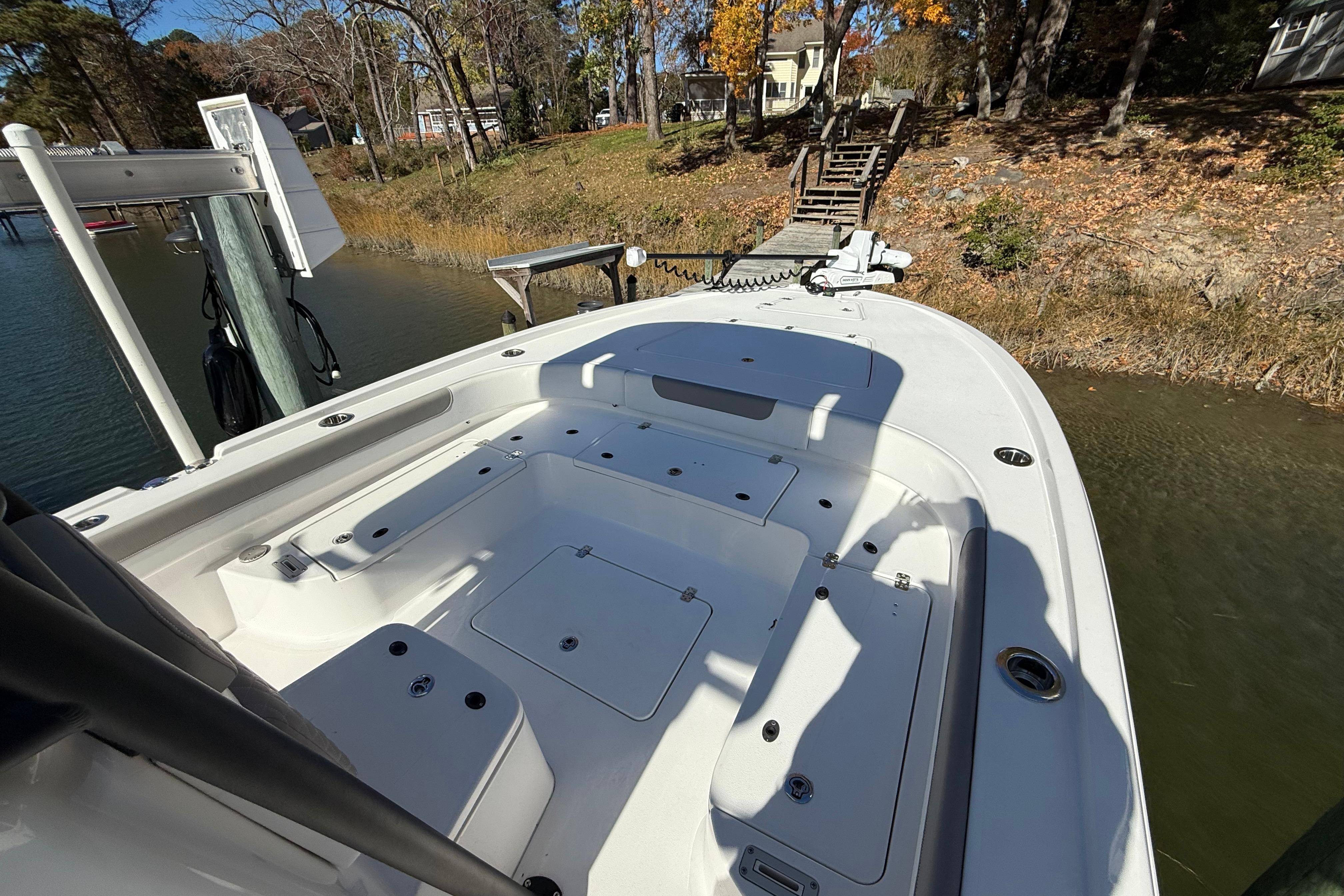 2023 Caymas 281 HB boat docked by a wooded shoreline in autumn.