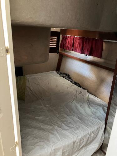 1985 Cruisers Yachts 338 Chateau Vee cabin interior with bed and red curtains.
