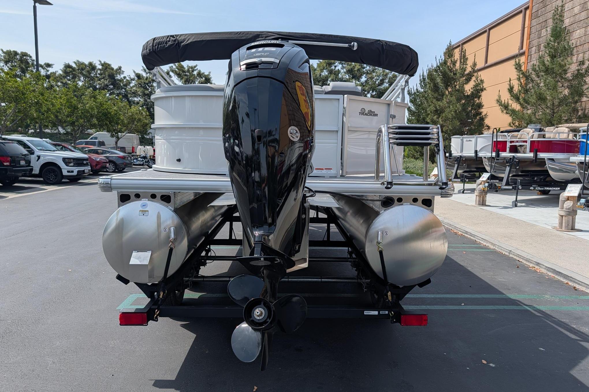 2026 Sun Tracker Party Barge 20 DLX pontoon boat with outboard motor, parked outdoors.