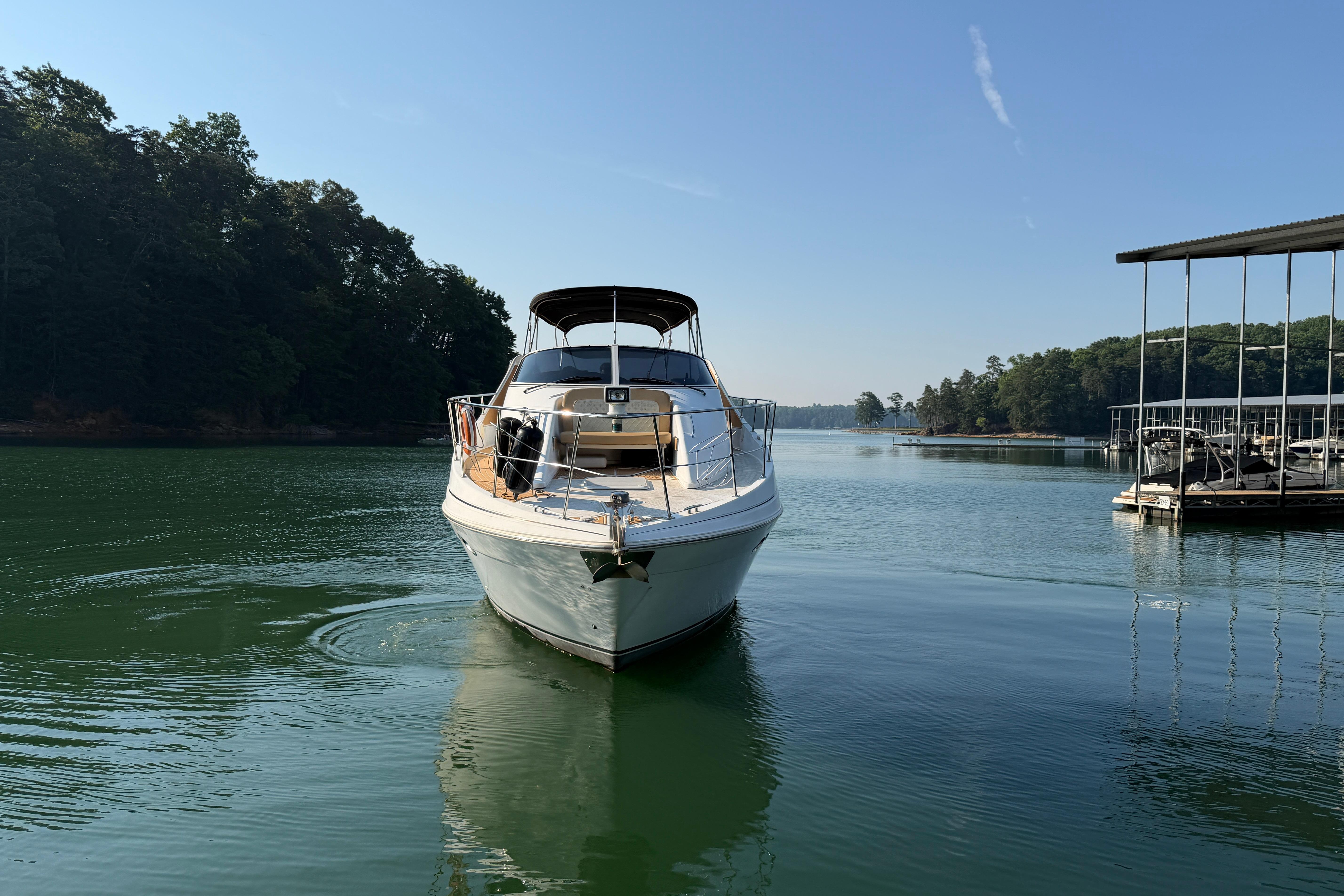 2003 Carver 350 Mariner yacht on serene lake with lush forest backdrop.