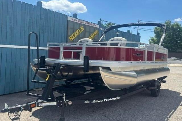 2026 Sun Tracker Bass Buggy 16 XL Select pontoon boat on trailer, parked outdoors.