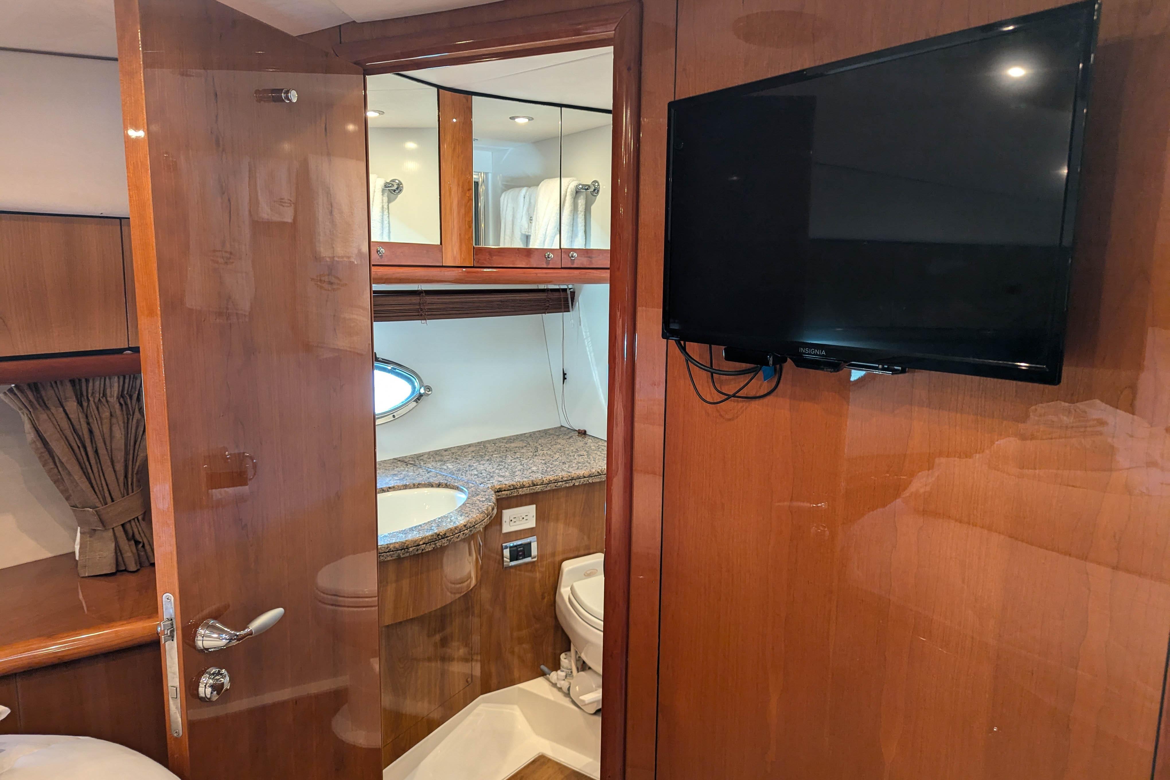 Luxurious bathroom interior of 2006 Sunseeker Predator 68 yacht with TV and wooden finish.