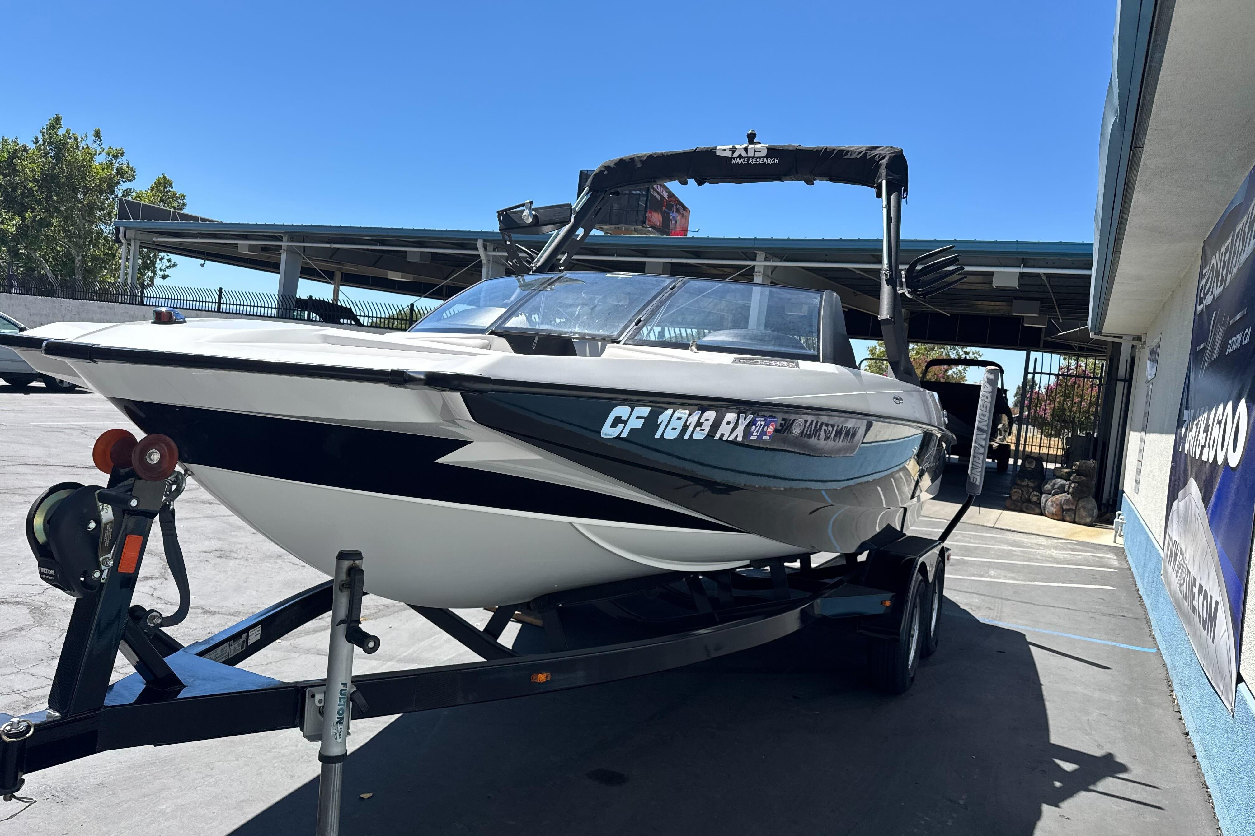 2015 Axis A20 boat on trailer, parked outdoors under clear blue sky.