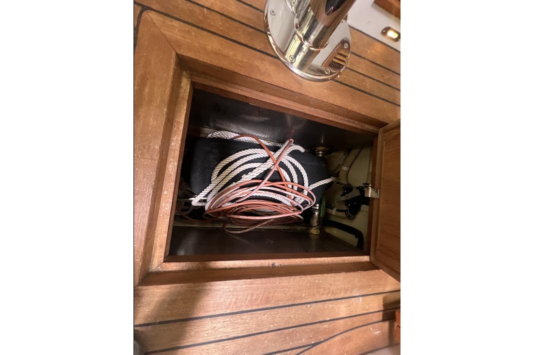 Storage compartment on 2004 RB DERELI Daytripper 40 with coiled ropes and wooden finish.