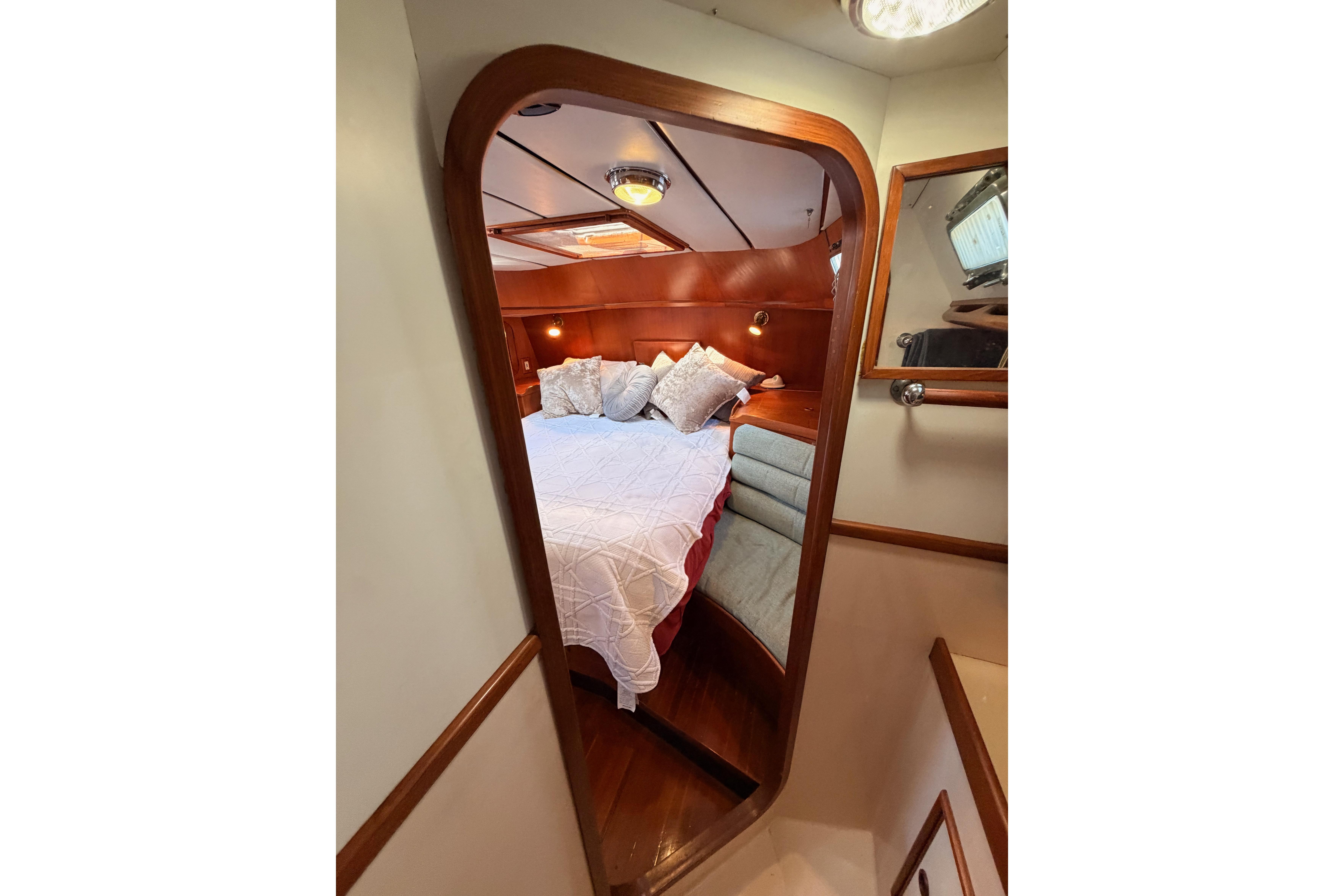 Cozy cabin interior of 1991 Hylas 51 yacht with wooden accents and plush bedding.
