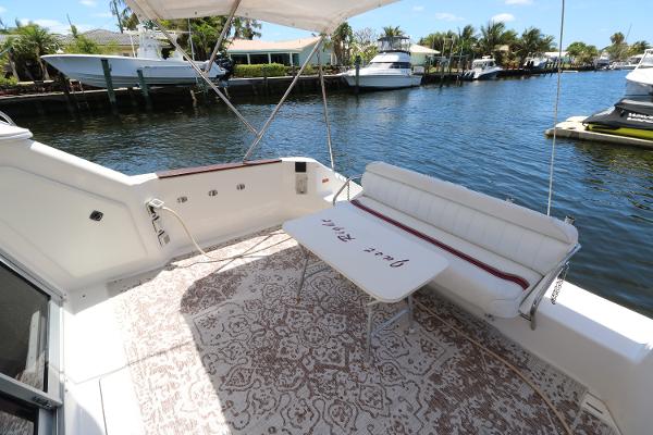 1992 Sea Ray 350 Express Bridge boat deck with seating and table by the water.