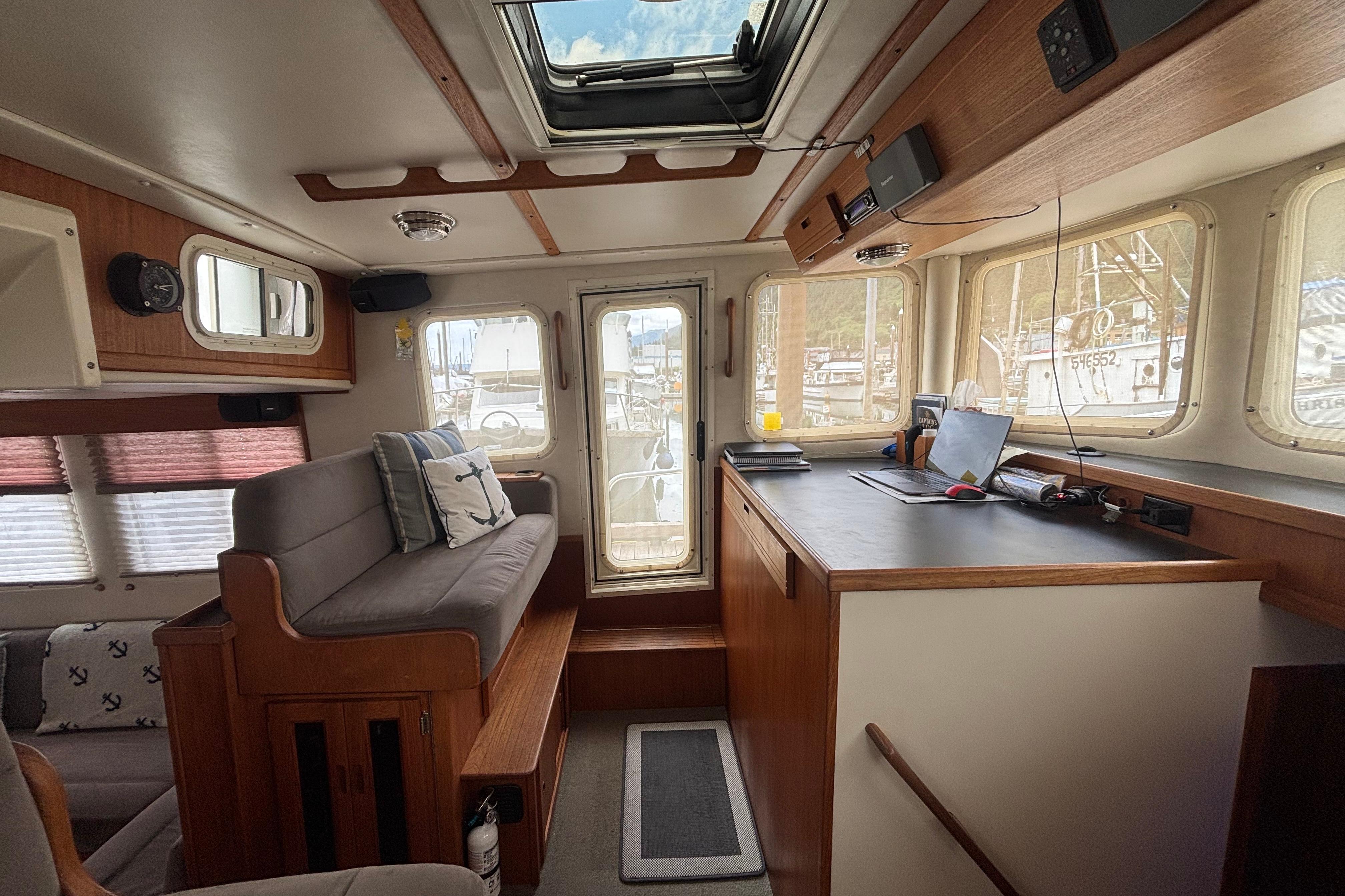 Interior of a 2004 Nordic Tug 37, featuring cozy seating and a navigation desk.