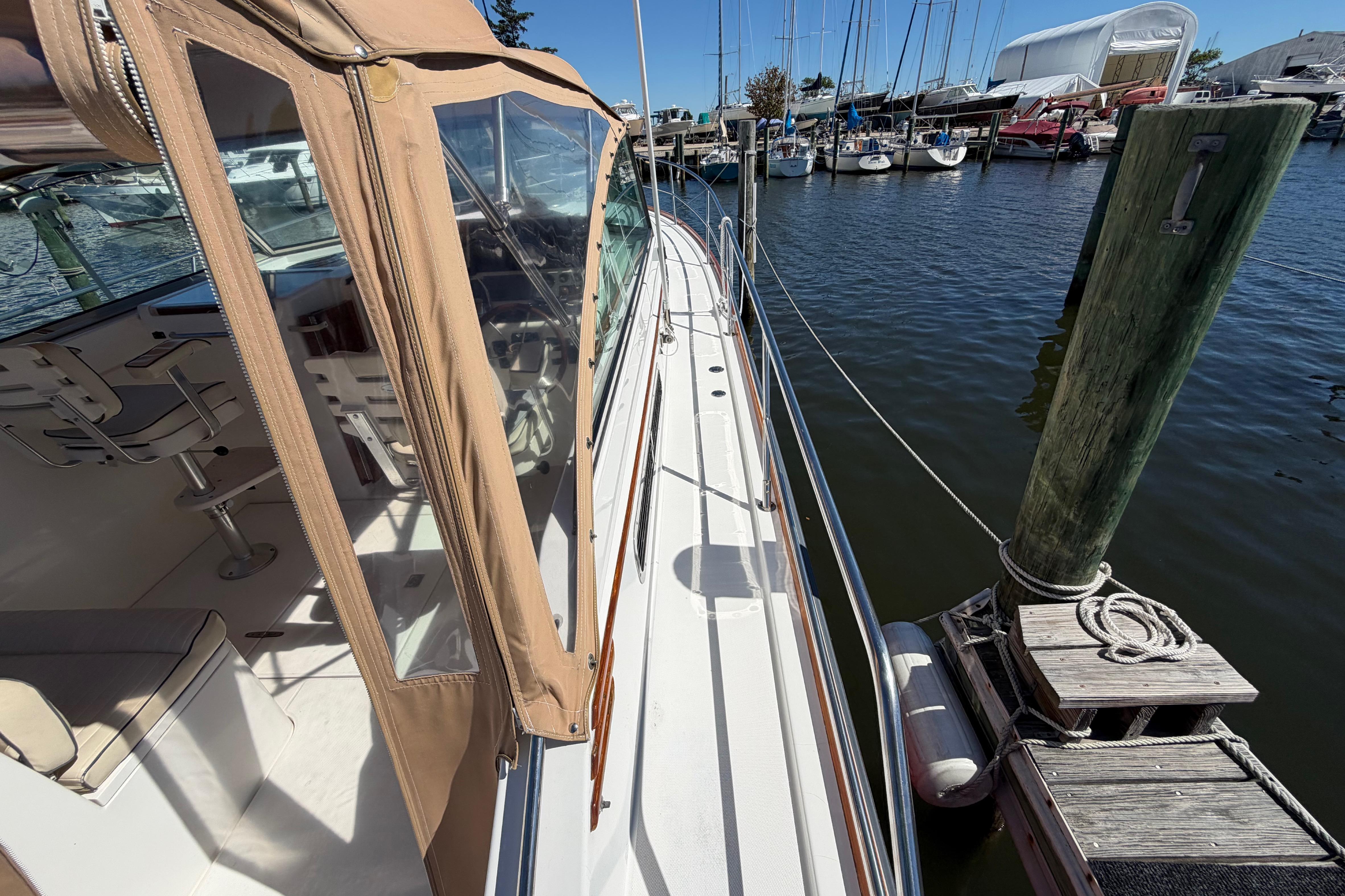 2000 Sabreline 36 Express yacht docked at marina, featuring tan canopy and sleek design.