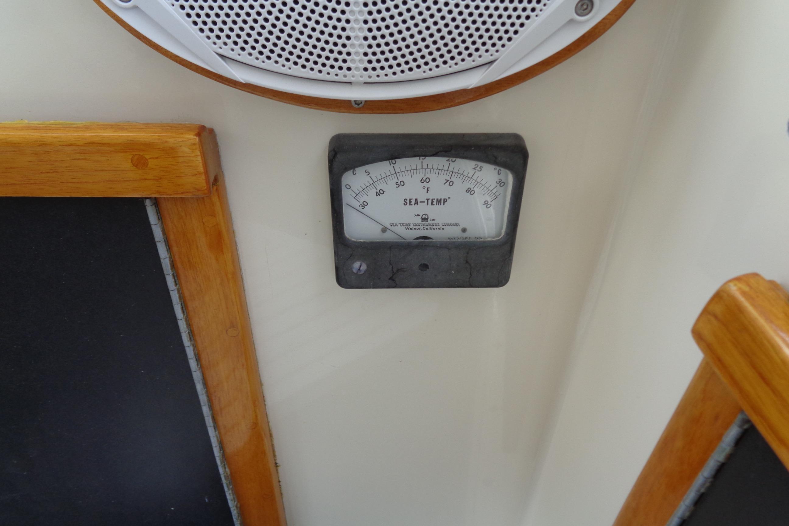 Sea temperature gauge on 1981 Hatteras 48 Cockpit Motor Yacht, surrounded by wood trim.