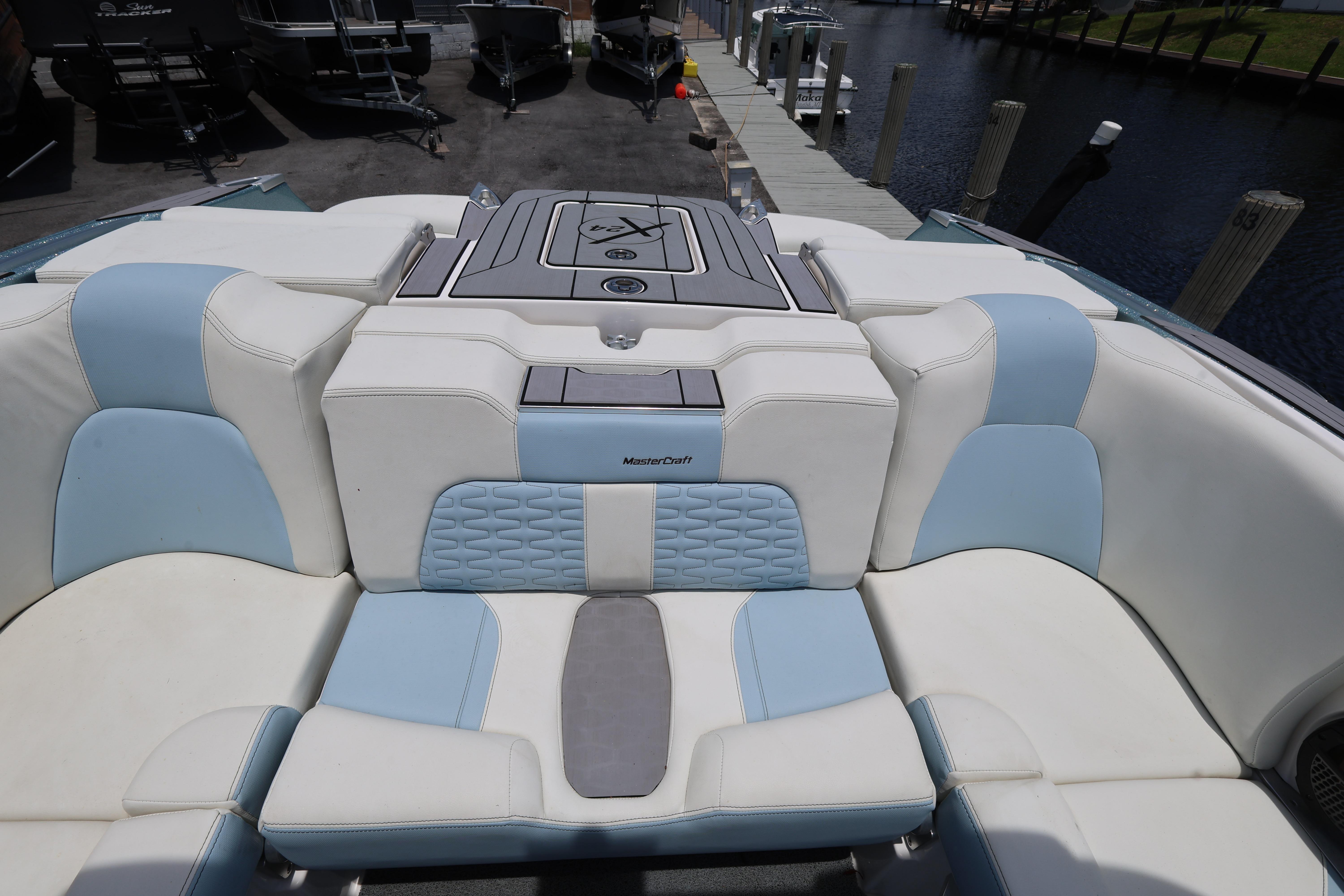 2023 MasterCraft X24 boat interior with white and blue seating at a dock.