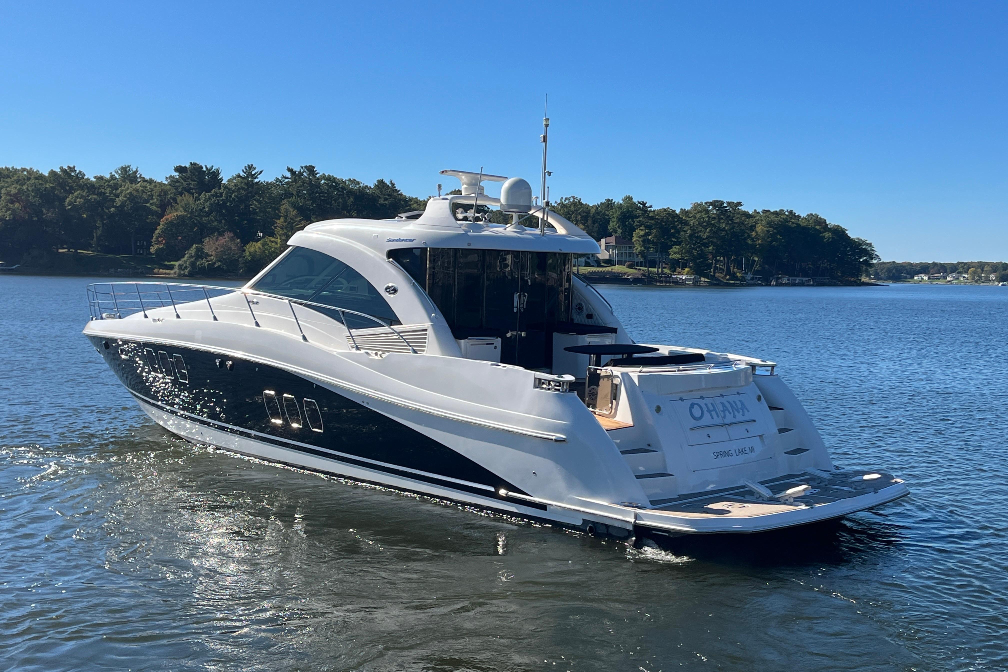 2007 Sea Ray 60 Sundancer yacht cruising on a serene lake under a clear blue sky.
