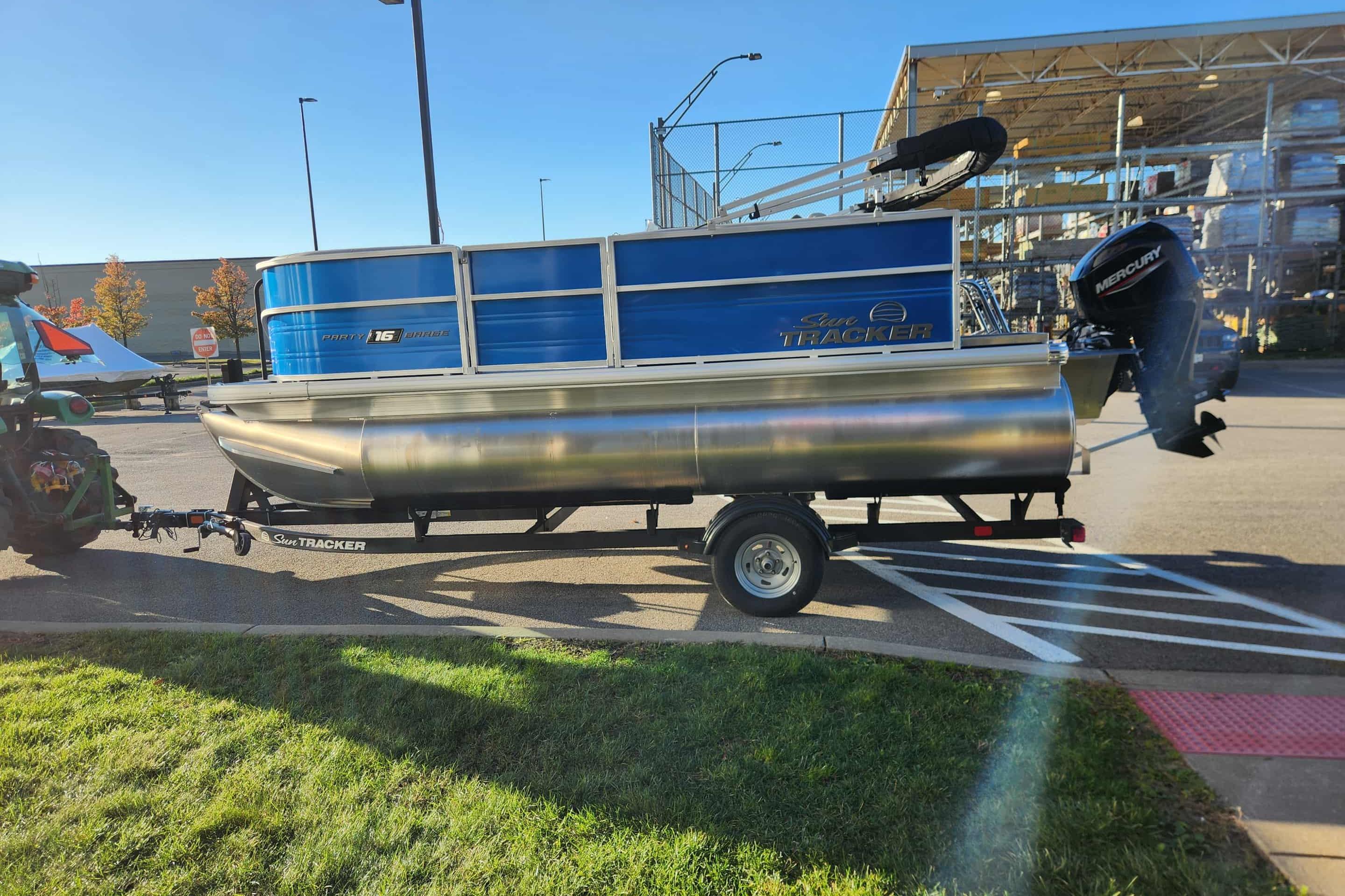 2026 Sun Tracker Party Barge 16 DLX pontoon boat on trailer in parking lot.