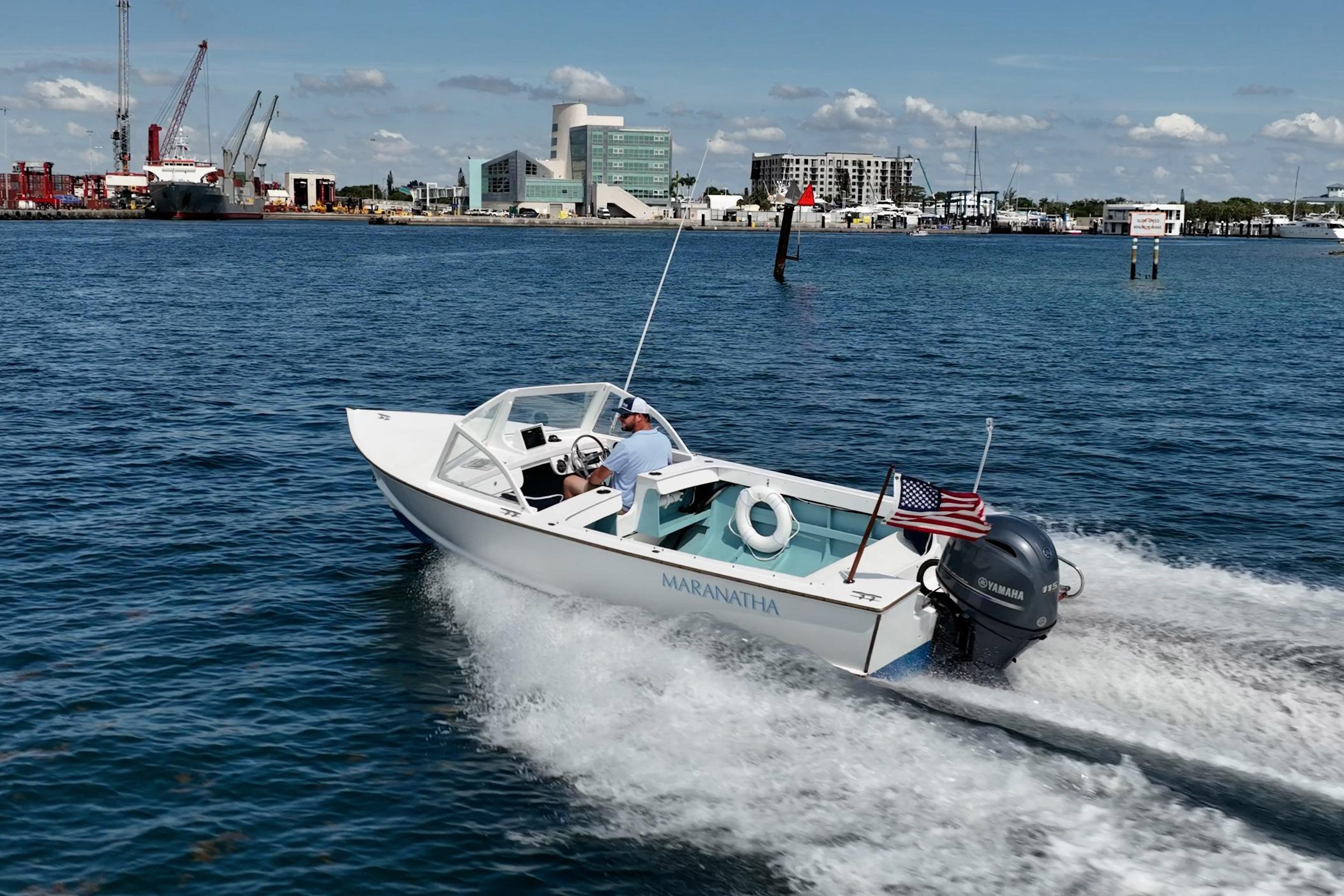 1982 Albury Brothers Runabout cruising in a harbor with cityscape background.