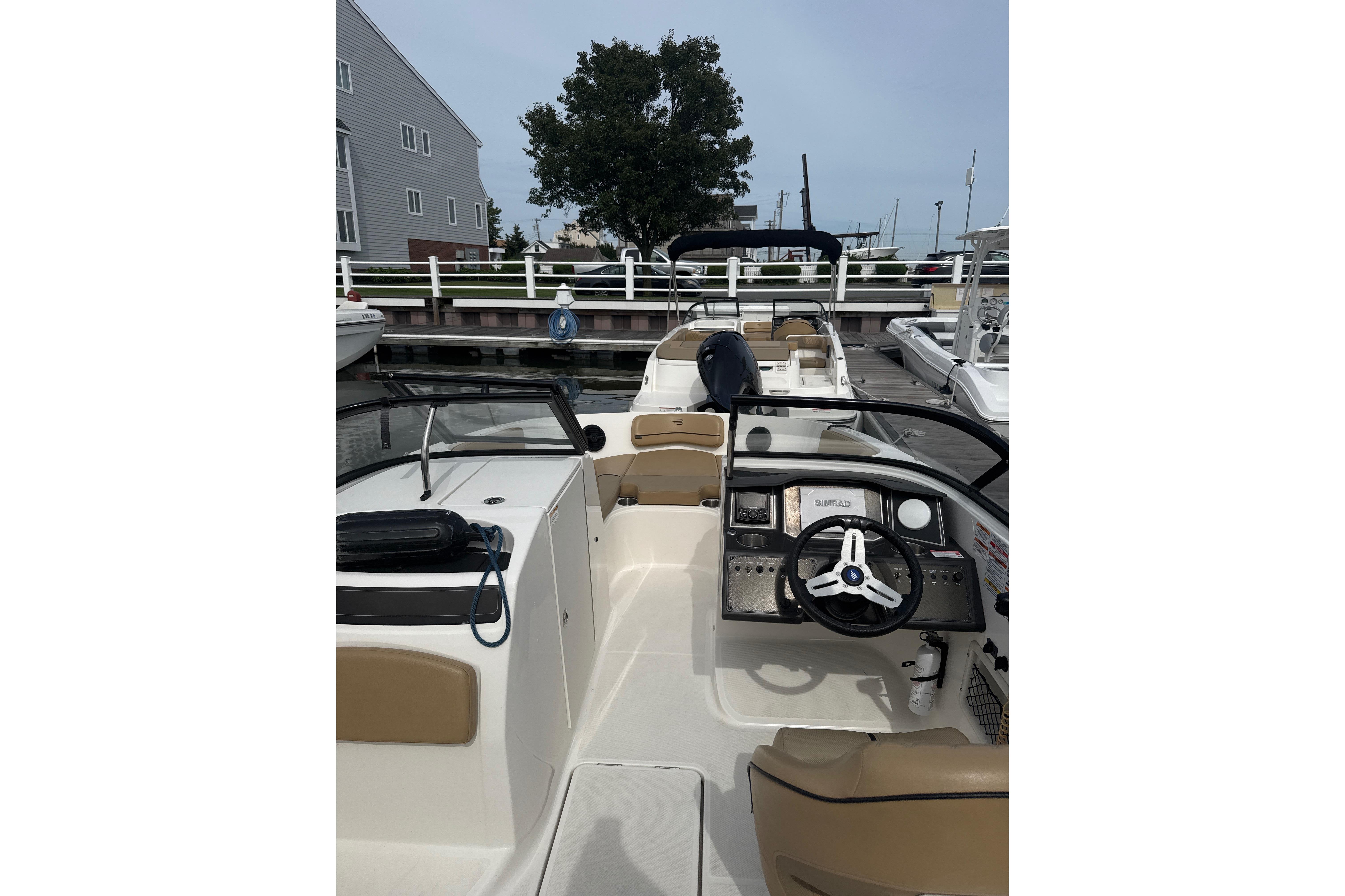 2025 Bayliner VR6 Bowrider OB interior view at dock, showcasing steering and seating area.